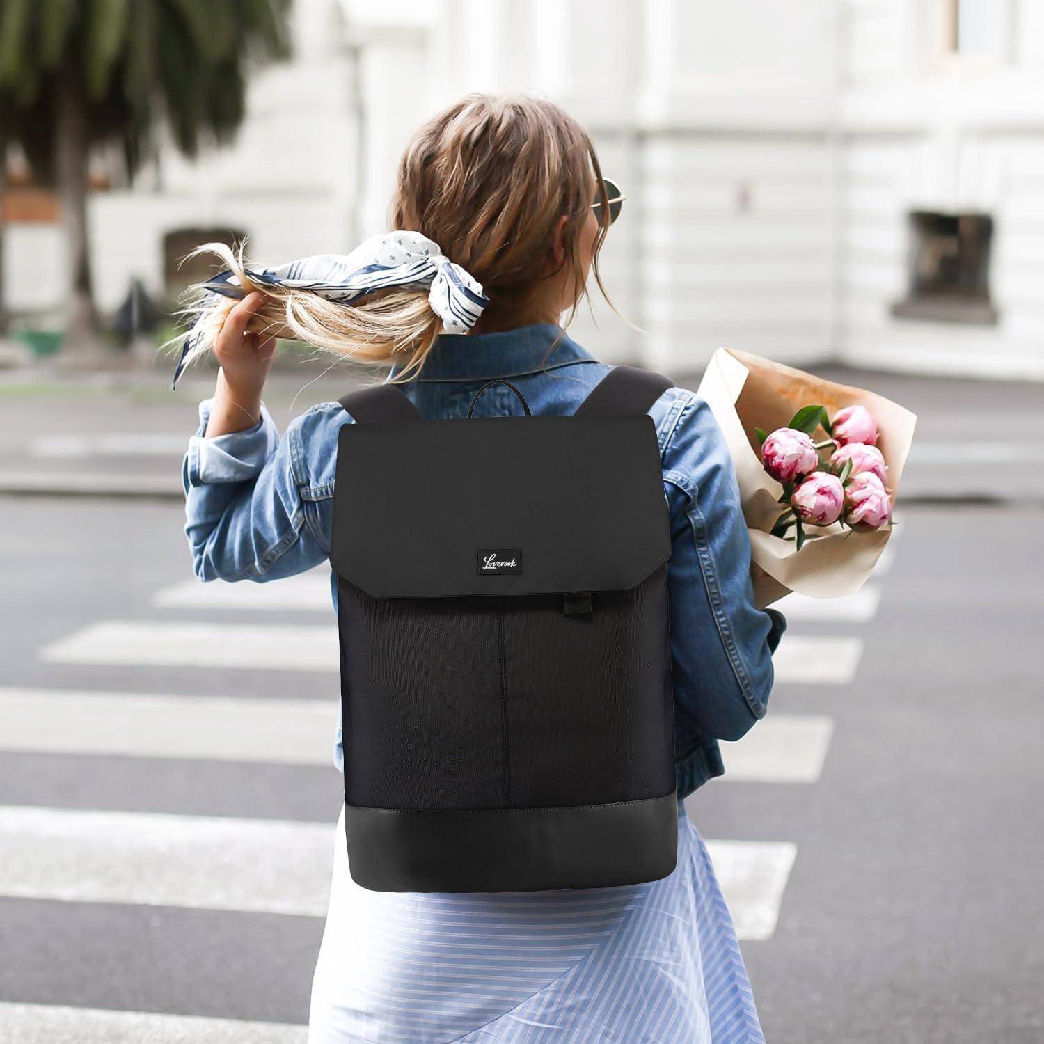 Eine Person mit einer Jeansjacke und einem schwarzen Rucksack hält auf einem Fußgängerüberweg inne und trägt einen Zopf. Sie hält einen Strauß pinker Blumen.