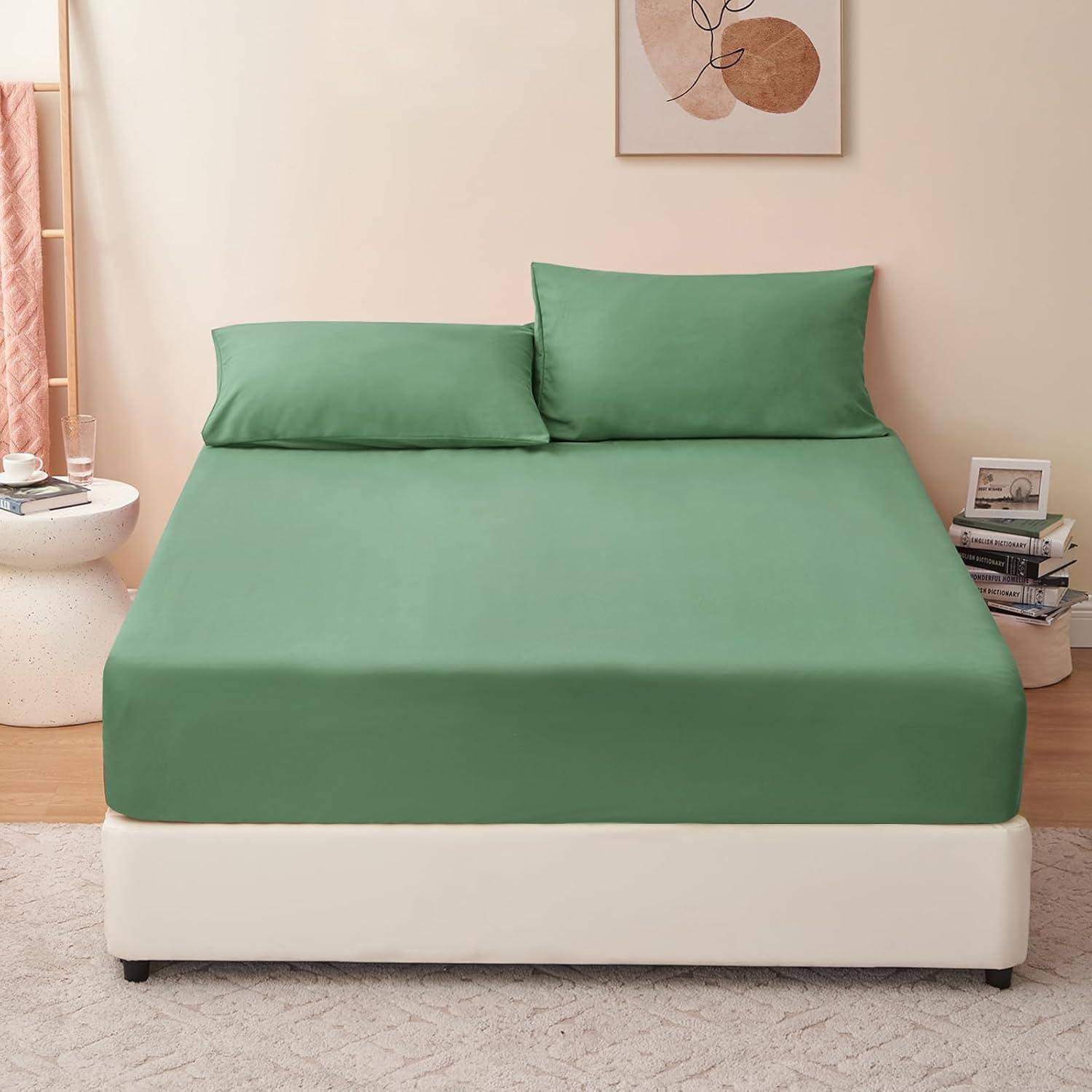 Ein ordentlich gemachtes Bett mit grüner Bettwäsche und zwei Kissen in einer modernen Schlafzimmereinrichtung; Nachttische mit Büchern und Kunst an der Wand.