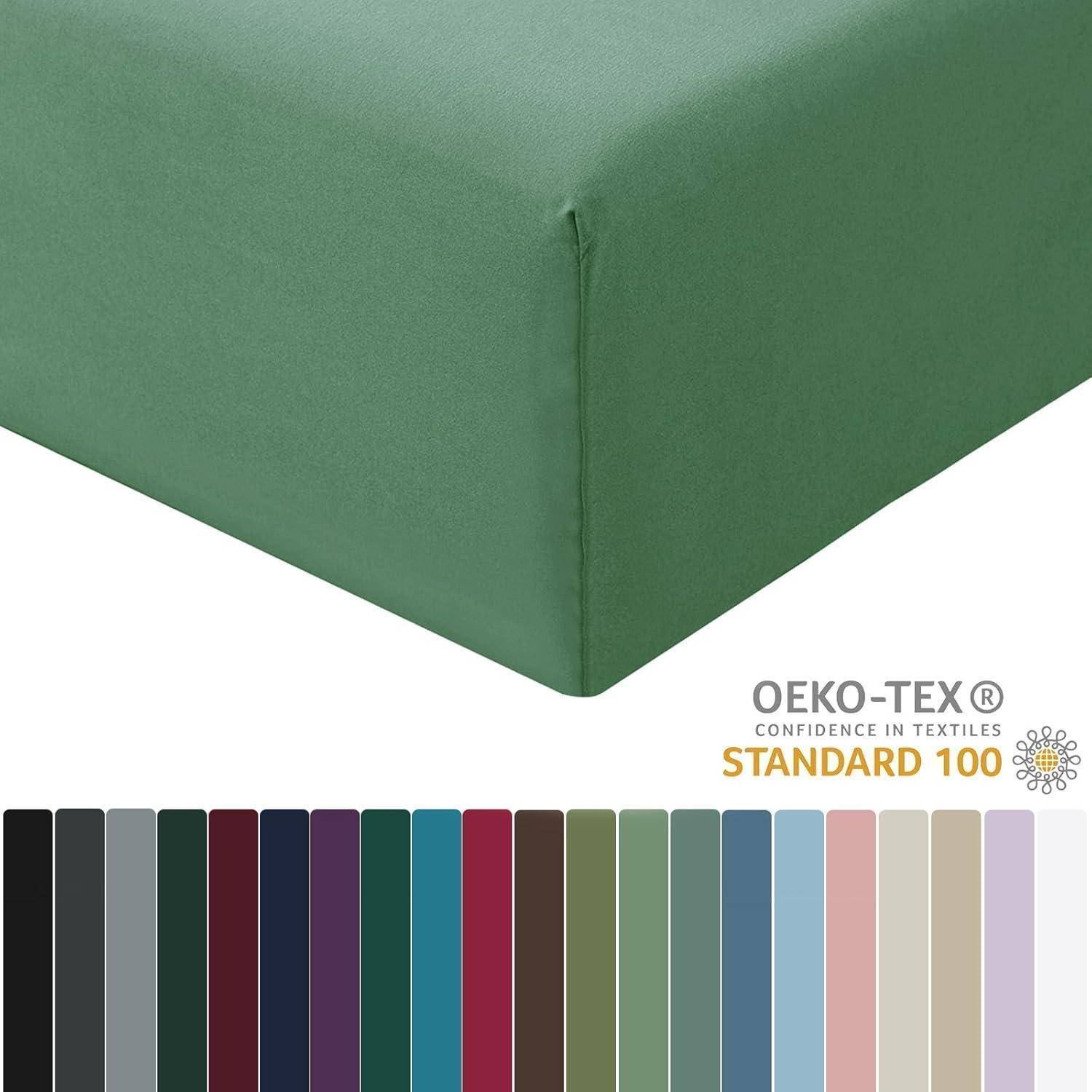 Ein grünes Spannbettlaken wird präsentiert, darunter eine Farbpalette mit verschiedenen Schattierungen. Das OEKO-TEX STANDARD 100 Logo weist auf die Zertifizierung hin.