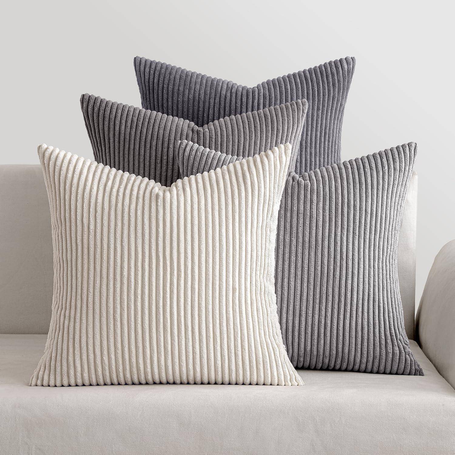 Vier gerippte Textur-Kissen in Creme- und Grautönen sind auf einem beigen Sofa angeordnet und schaffen eine gemütliche und neutrale Dekoration.
