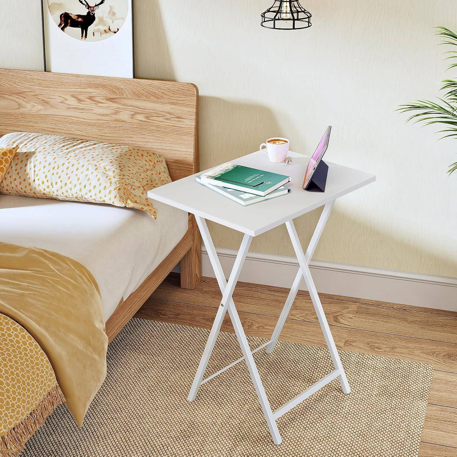 Eine Schlafzimmerszene mit einem Holzkopfteil, einem weißen Nachttisch, auf dem sich ein Buch, eine Tasse und ein Tablet befinden. Ein Bett mit gelben und weißen Bettwäschestücken.