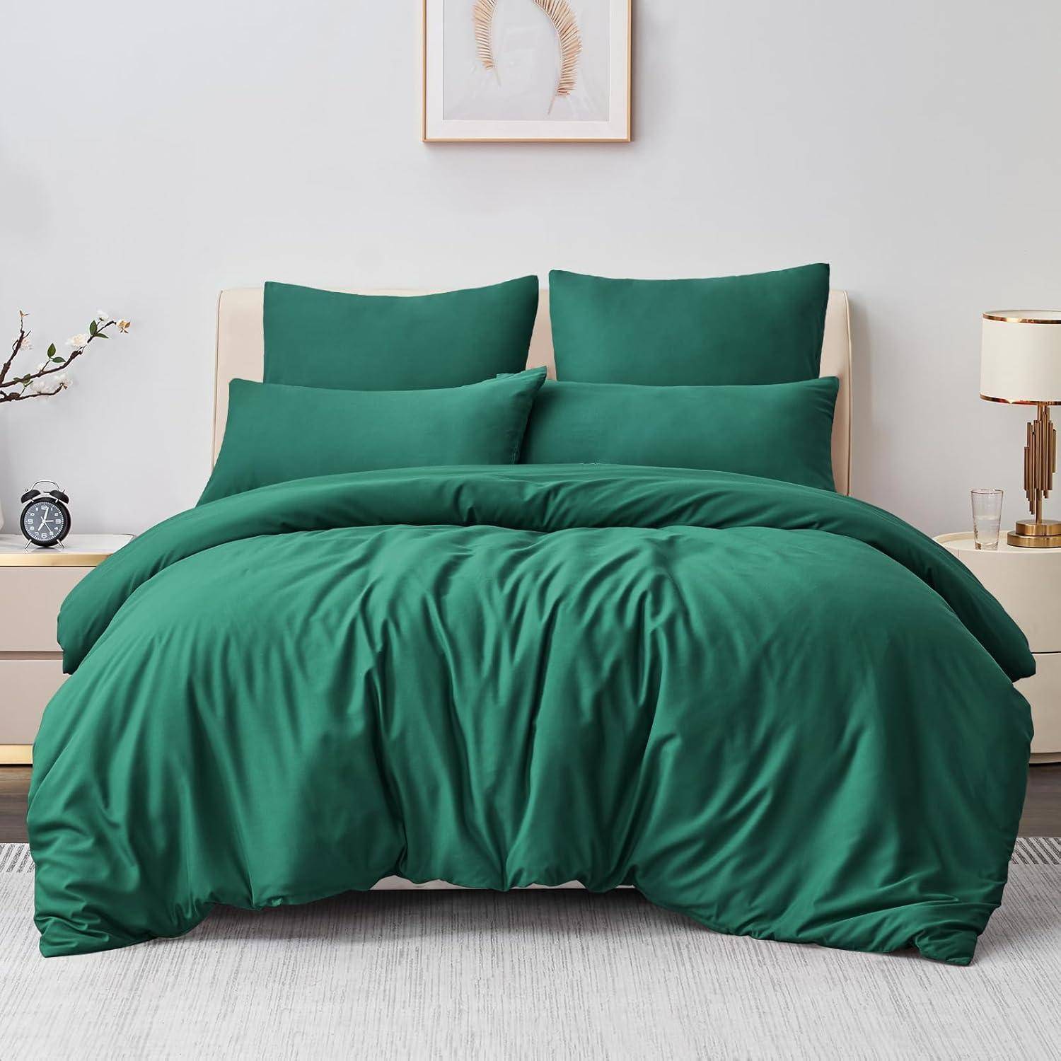 Ein ordentlich gemachtes Bett mit einer lebhaft grünen Bettdecke und Kissen. Eine Pflanze, eine Lampe und ein gerahmtes Kunstwerk sind im Hintergrund sichtbar.