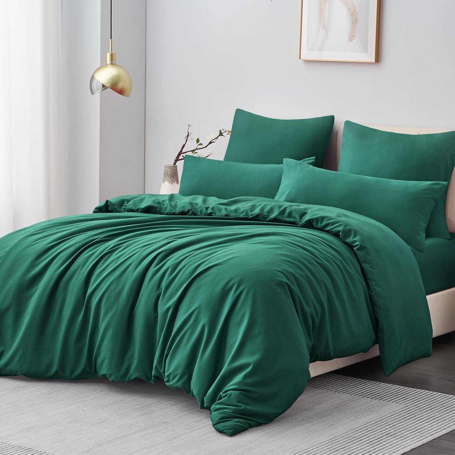 Ein Bett mit einem luxuriösen grünen Bettset, bestehend aus Kissen und Bettdecke, in einem modernen Schlafzimmer mit minimalistischer Einrichtung.