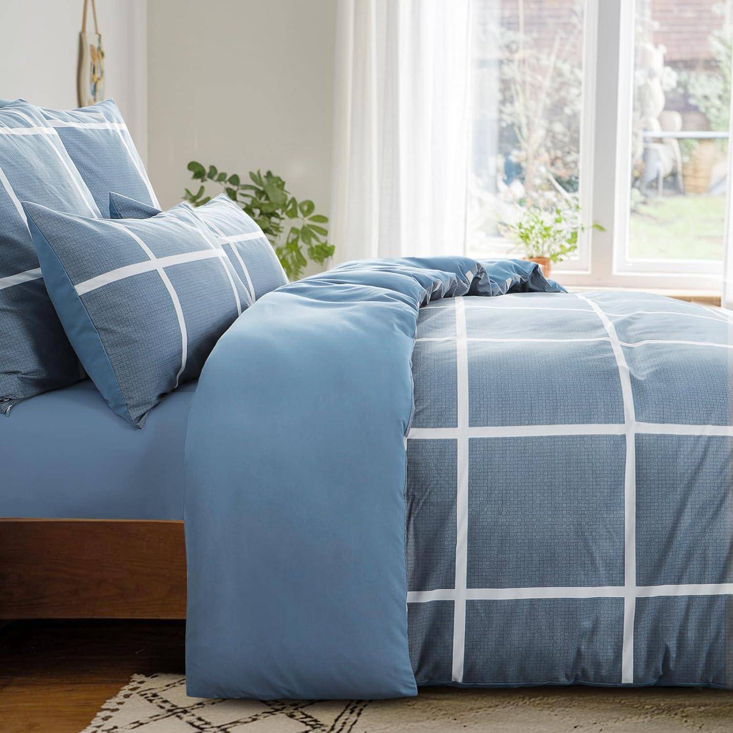 Ein ordentlich gemachtes Bett mit blau-weiß karierter Bettwäsche, unter einem großen Fenster mit transparenten Vorhängen, die eine helle und gemütliche Atmosphäre schaffen.