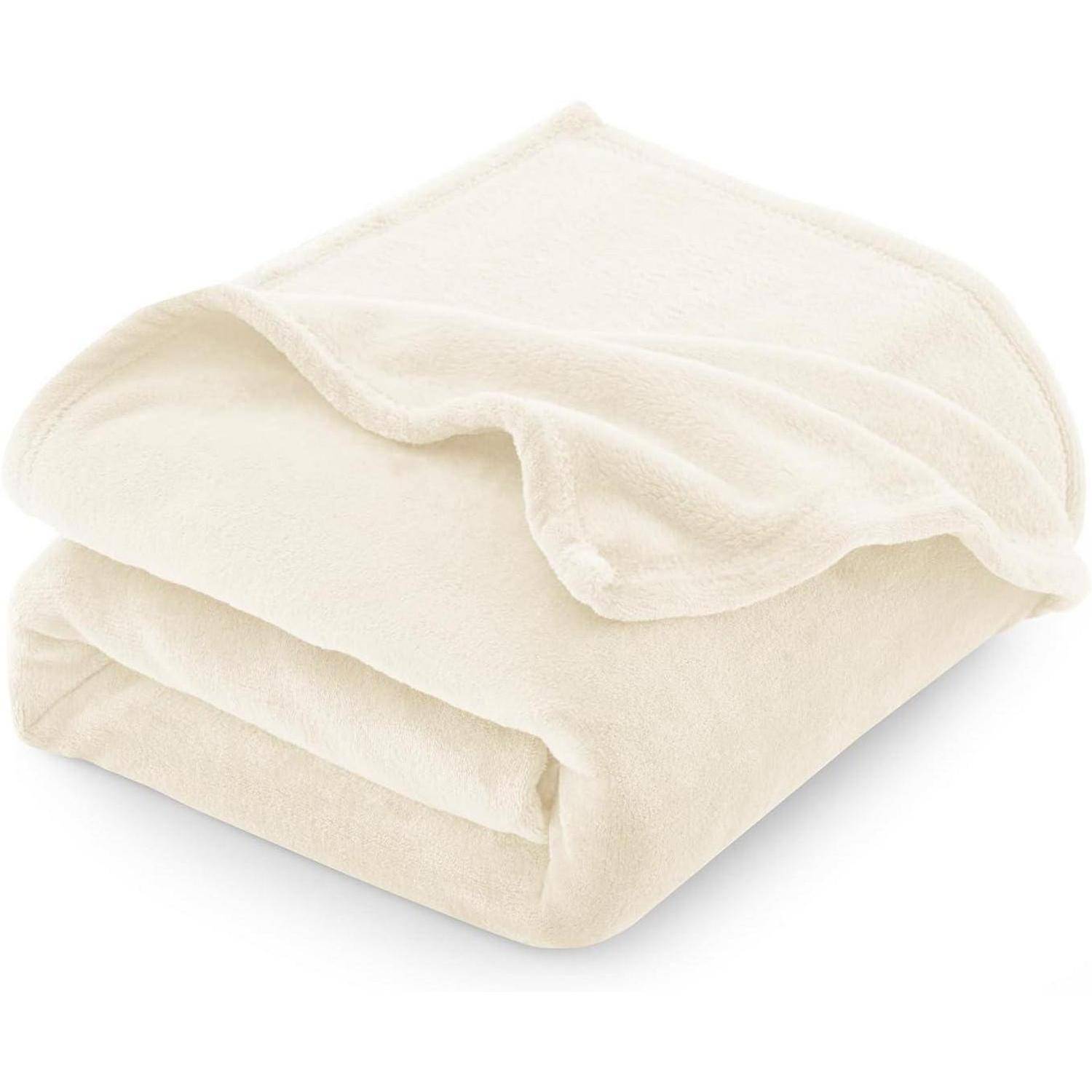 Eine weiche, gefaltete beige Decke liegt auf weißem Hintergrund und präsentiert ihre plüschige Textur und sauber genähten Kanten.