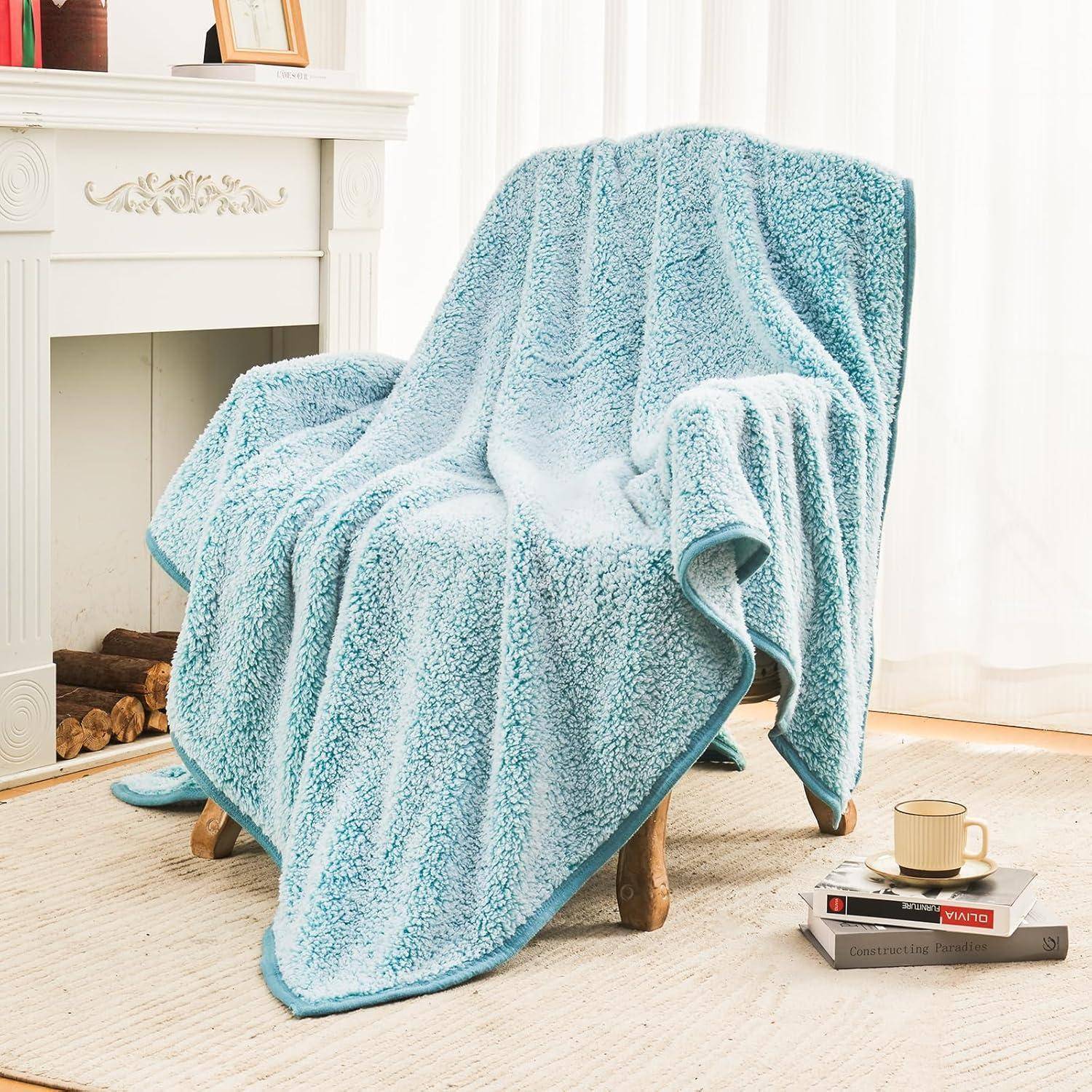 Ein gemütlicher Sessel, bedeckt mit einer flauschigen blauen Decke neben einem Kamin. Ein kleiner Tisch trägt eine Teetasse und Bücher und deutet auf eine entspannende Atmosphäre hin.