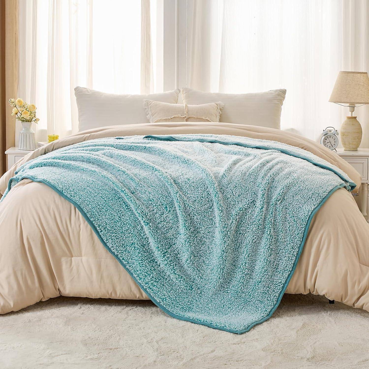 Ein ordentlich gemachtes Bett mit weißen Laken und einer großen, hellblauen Plüschdecke, die darüber drapiert ist, in einem sanft beleuchteten Schlafzimmer mit hellen Einrichtungselementen.