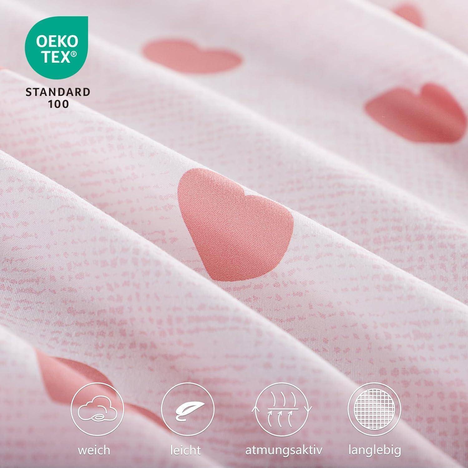 Rosa Stoff mit Herzmuster, gekennzeichnet mit 'OEKO-TEX STANDARD 100'. Icons am unteren Rand beschreiben den Stoff als weich, leicht, atmungsaktiv und strapazierfähig.