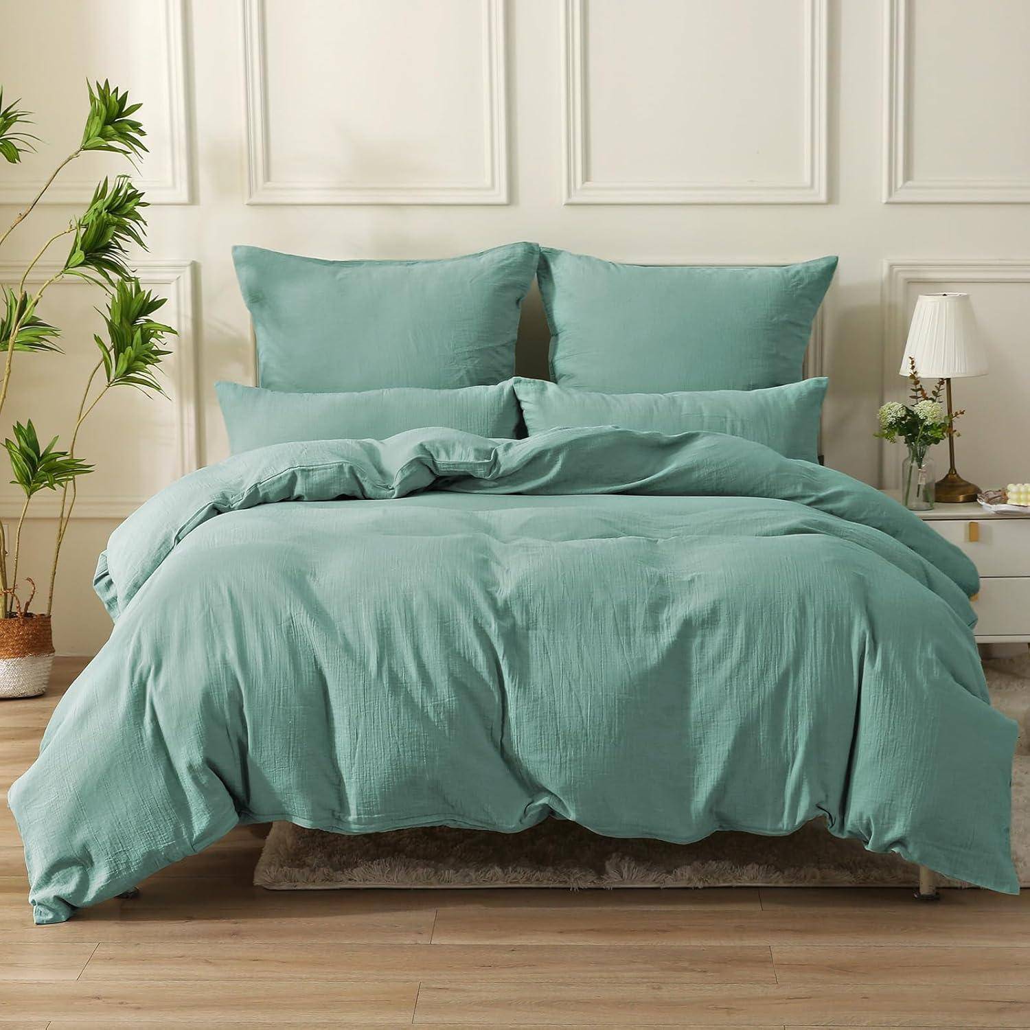 Ein sorgfältig gemachtes Bett mit petrolfarbener Bettwäsche, einschließlich Kissen und Bettdecke, umgeben von einer kleinen Pflanze und einem Nachttisch mit einer Lampe.