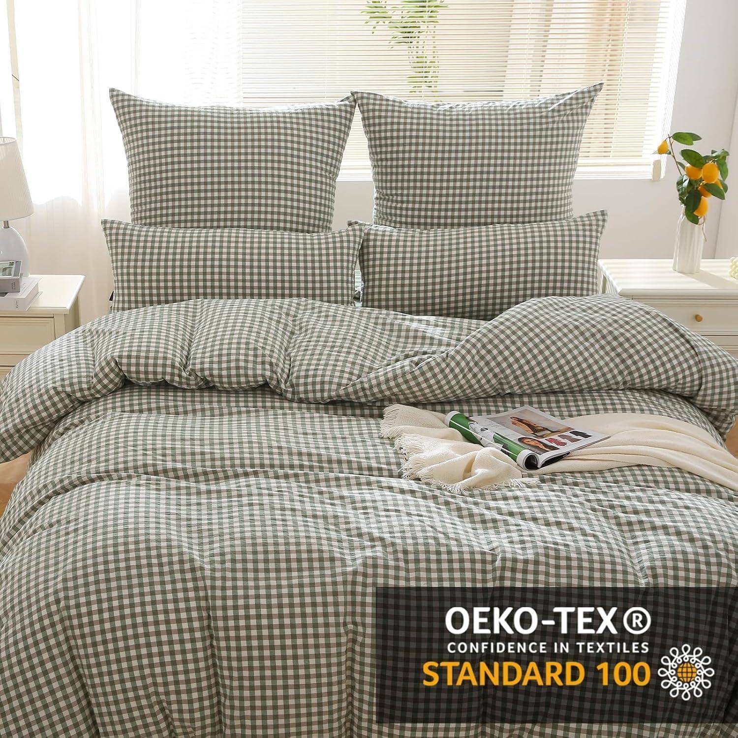 Ein ordentlich gemachtes Bett mit einer grauen karierten Bettdecke und Kissen. Ein Nachttisch mit Büchern und einer Pflanze steht daneben. Text lautet ‚OEKO-TEX® STANDARD 100'.