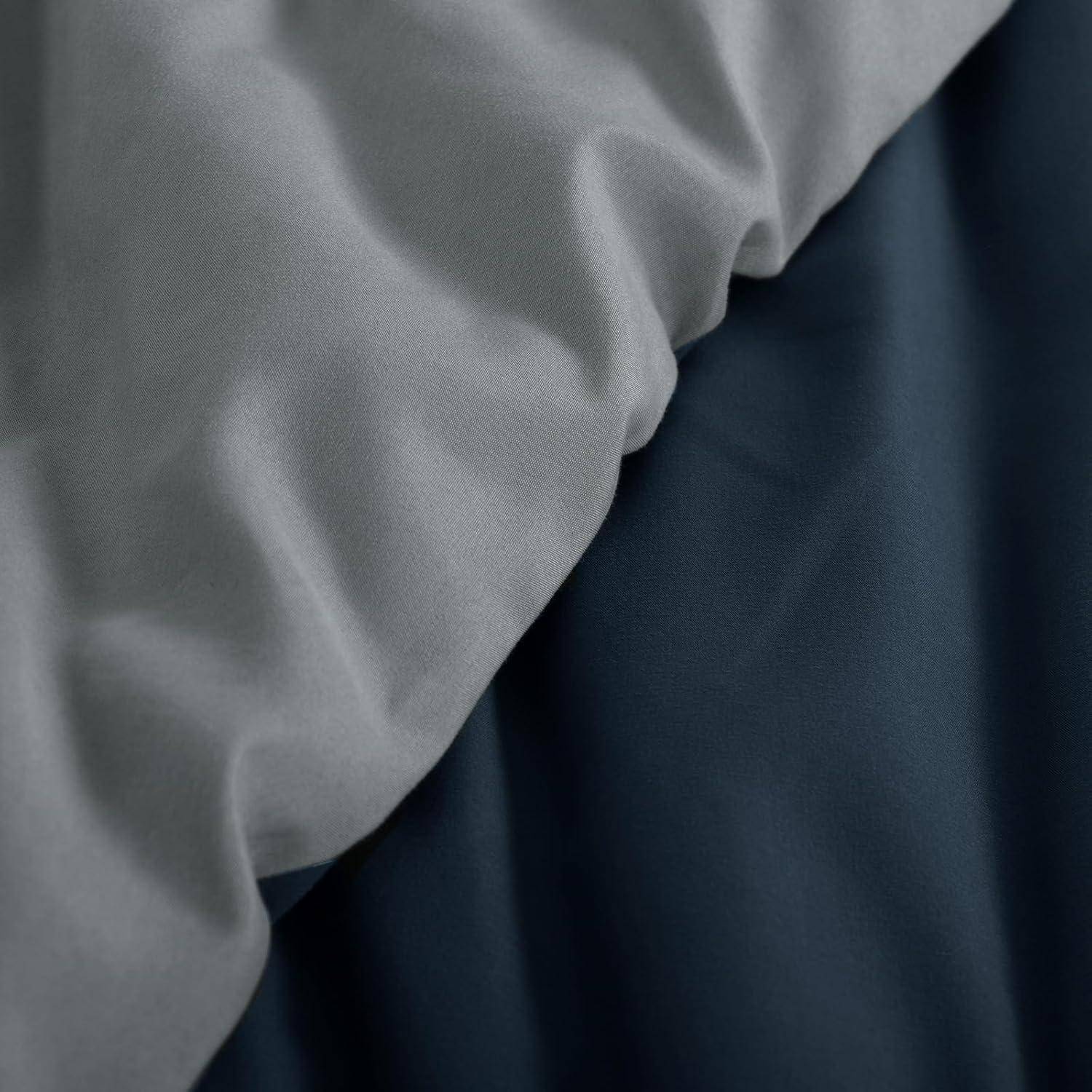 Nahaufnahme eines zerknitterten grauen Stoffes neben glattem dunkelblauen Stoff, die den Kontrast von Textur und Farbe hervorhebt.