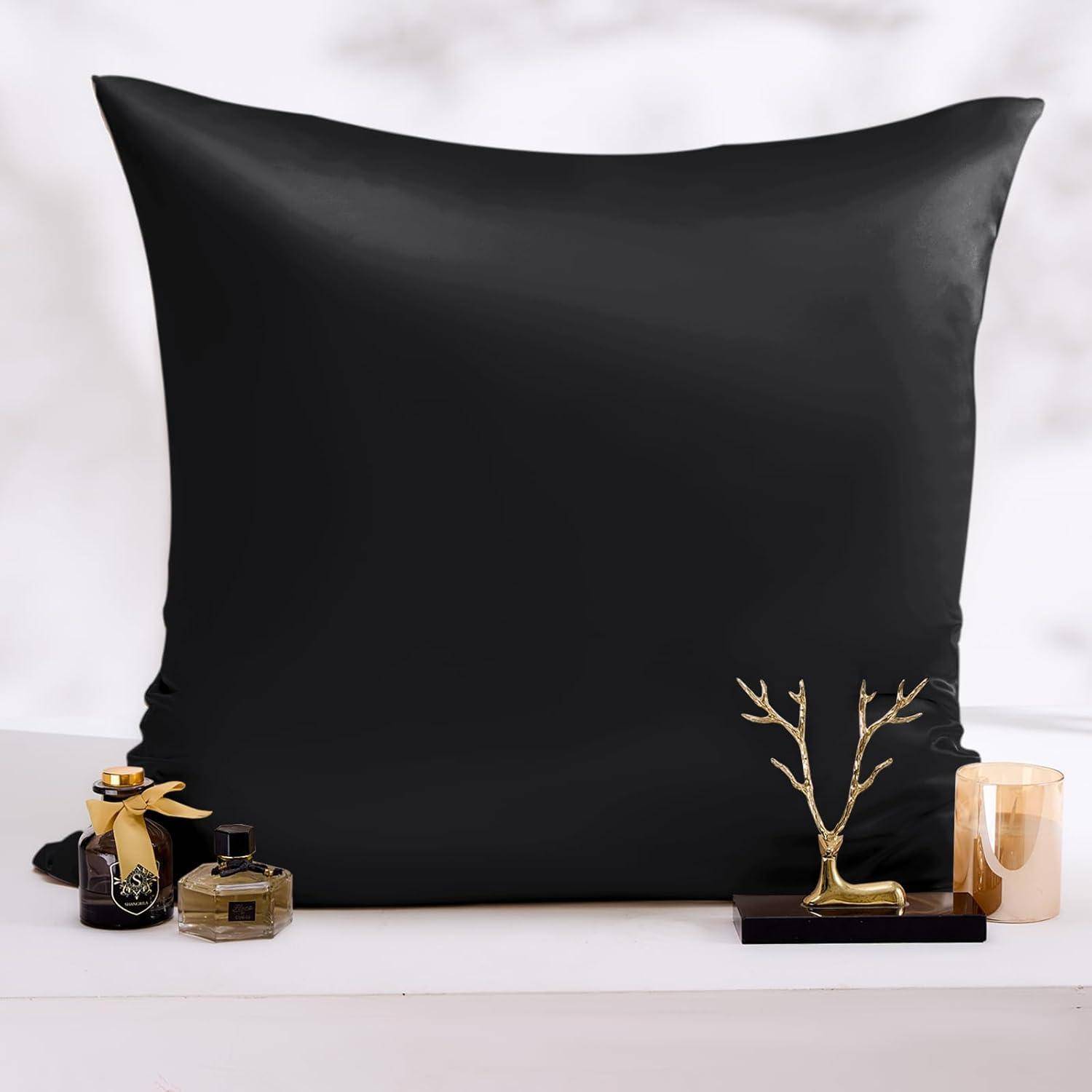 Ein luxuriöser schwarzer Kissenbezug auf einem Bett, flankiert von Parfümflakons und einer goldenen baumartigen Verzierung, die eine elegante Nachttischdekoration schafft.