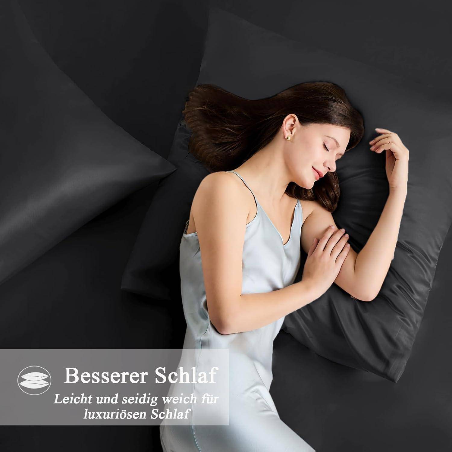 Eine Frau schläft friedlich auf einem Set aus dunkelgrauen Seidenkissenbezügen. Text lautet: Besserer Schlaf, Leicht und seidig weich für luxuriösen Schlaf.