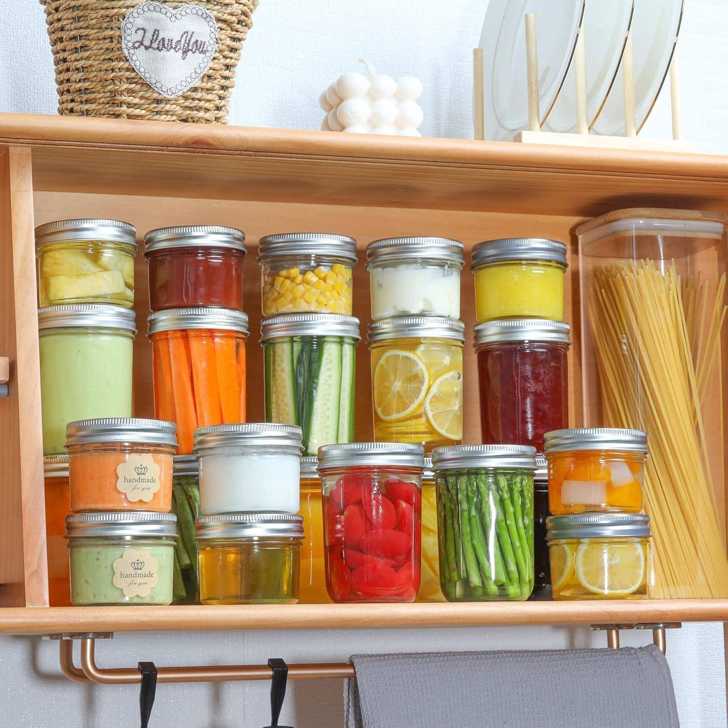 Ein Küchenregal mit sorgfältig angeordneten Glasgefäßen, gefüllt mit buntem Gemüse, Pasta und Gewürzen. Ein Weidenkorb mit der Aufschrift ‚Lebensmittel' steht oben darauf.