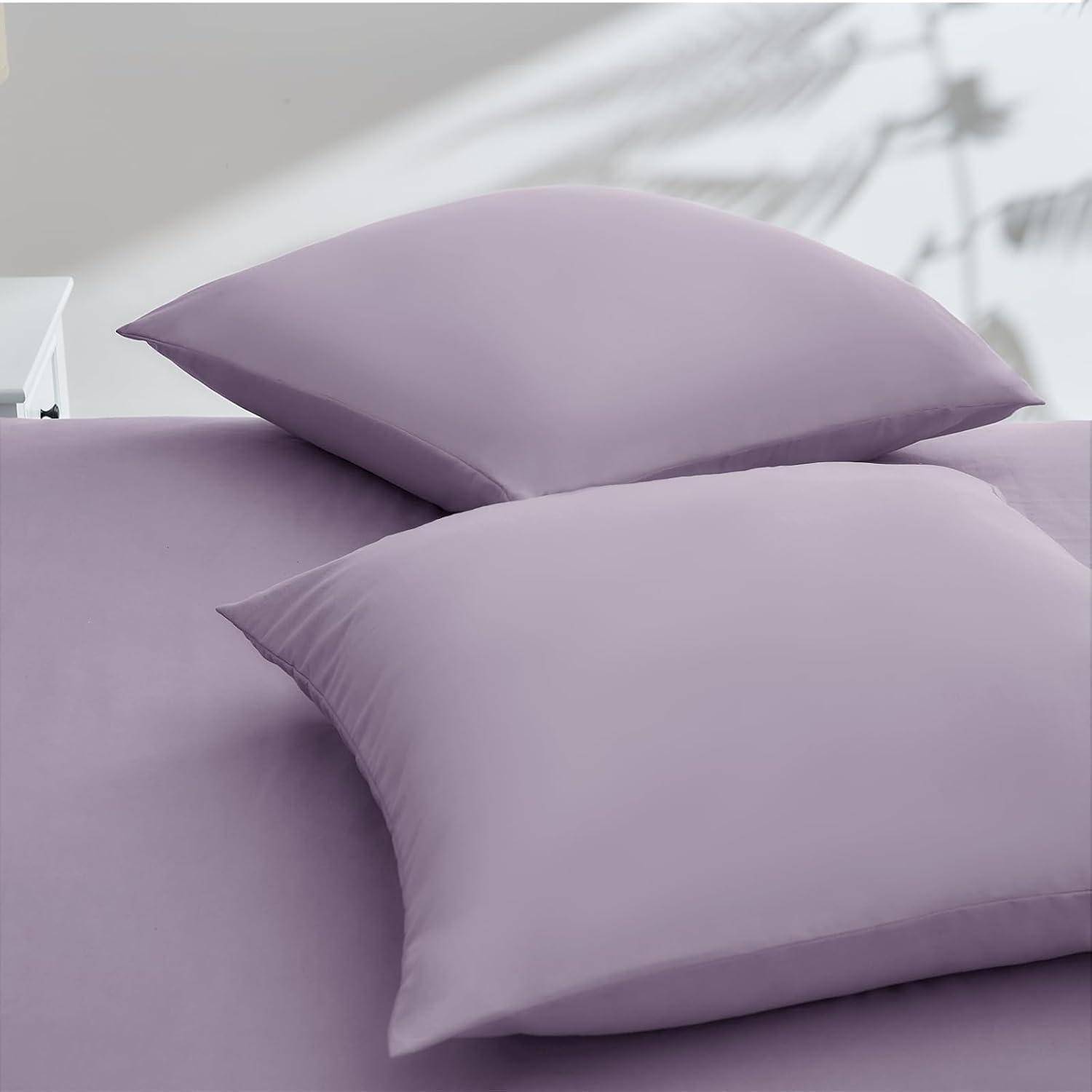 Zwei Lavendel-Kissen werden auf einem Bett mit Lavendenlaken platziert und erzeugen eine monochromatische und beruhigende Atmosphäre.