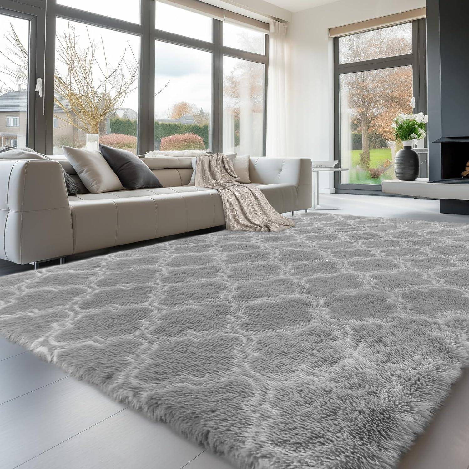 Ein heller, moderner Wohnraum mit großen Fenstern, einem üppigen grauen Teppich und einem weißen Sofa. Durch die Fenster sind Bäume zu sehen.