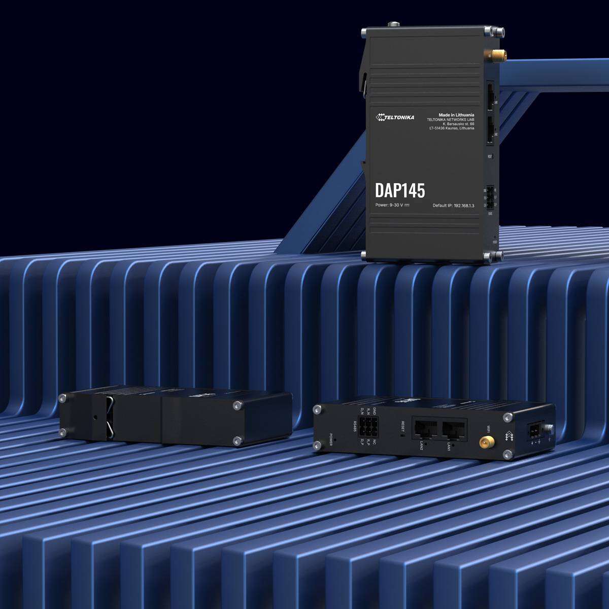 Eine Reihe elektronischer Geräte auf einer gerippten blauen Oberfläche, mit Anschlüssen und Steckverbindern, wobei eines der Geräte aufrecht steht und eine Beschriftung zeigt.