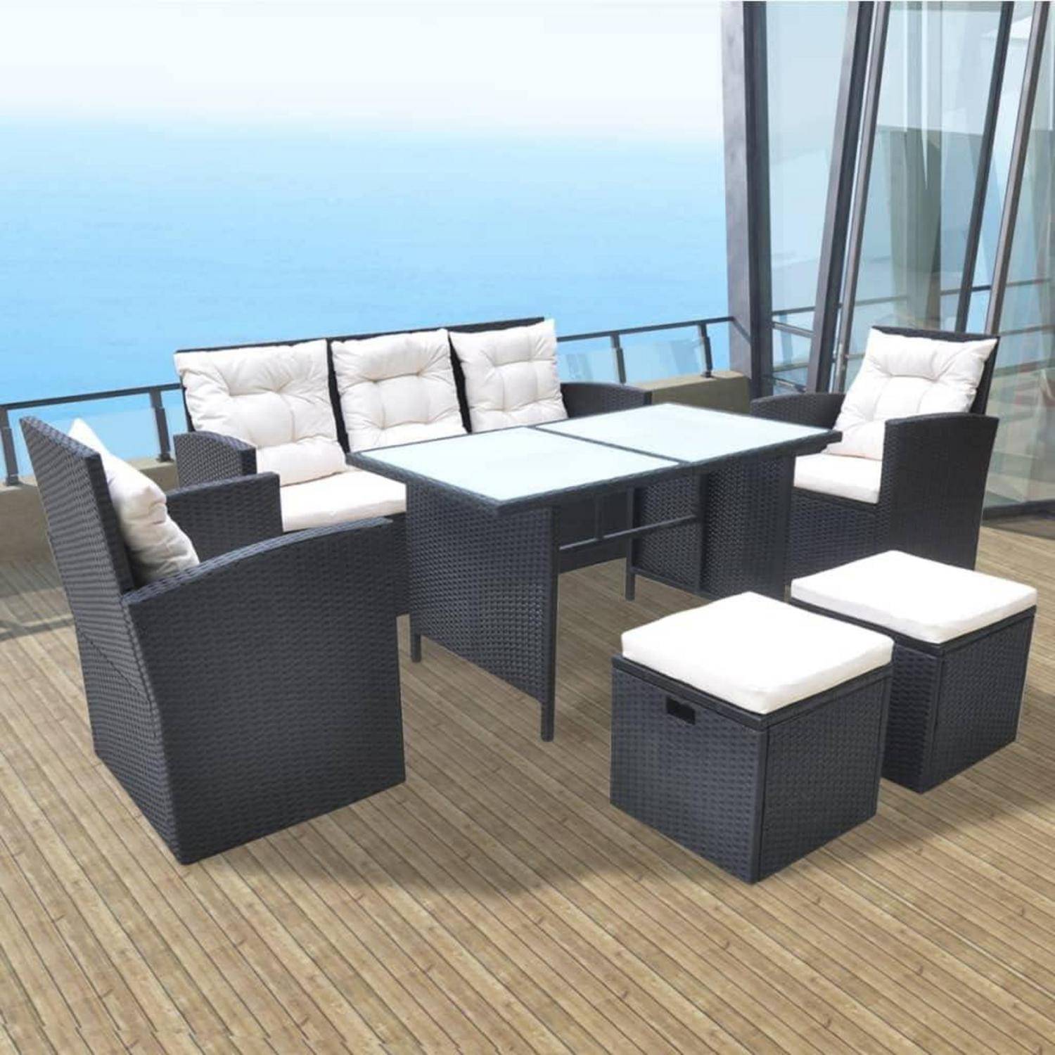 Outdoor-Terrassenmöbel auf einer Holzterrasse mit Blick aufs Meer, bestehend aus gepolsterten Stühlen, einem Sofa und einem Glastisch.