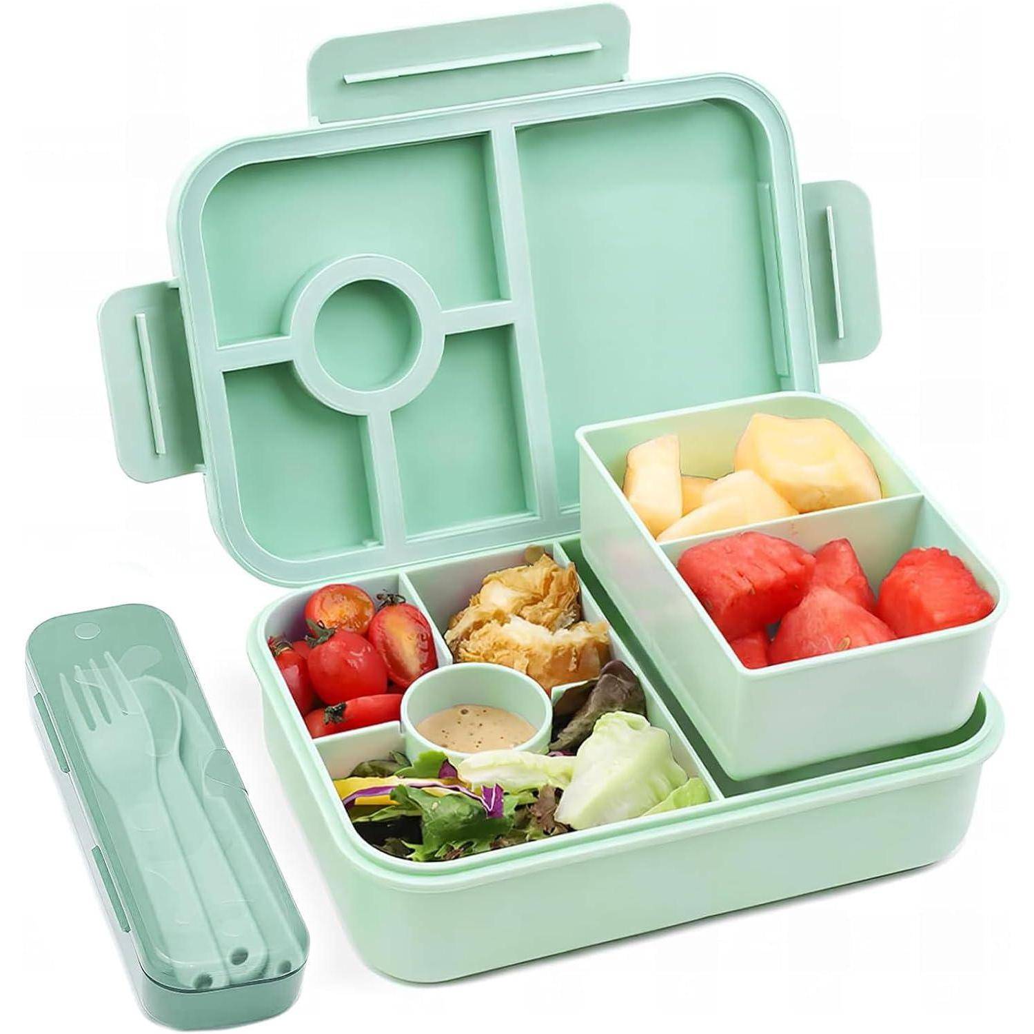 Eine grüne Bento-Lunchbox mit separaten Fächern, die Obst, Salat, Kirschtomaten, Nüsse und einen kleinen Behälter mit Dressing enthalten; Besteck inklusive.
