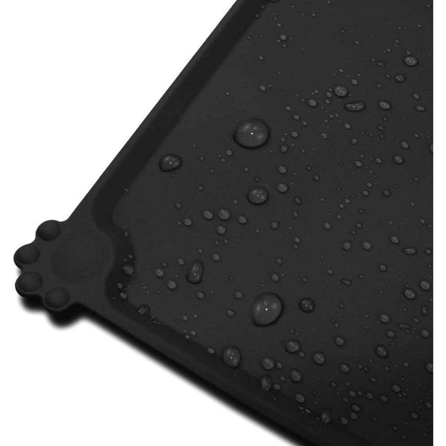 Nahaufnahme einer schwarzen, strukturierten Matte mit Wassertropfen, die über ihre Oberfläche verstreut sind und auf Wasserresistenz hinweisen. Eine Ecke der Matte ist sichtbar mit kreisförmigen Griffnoppen.
