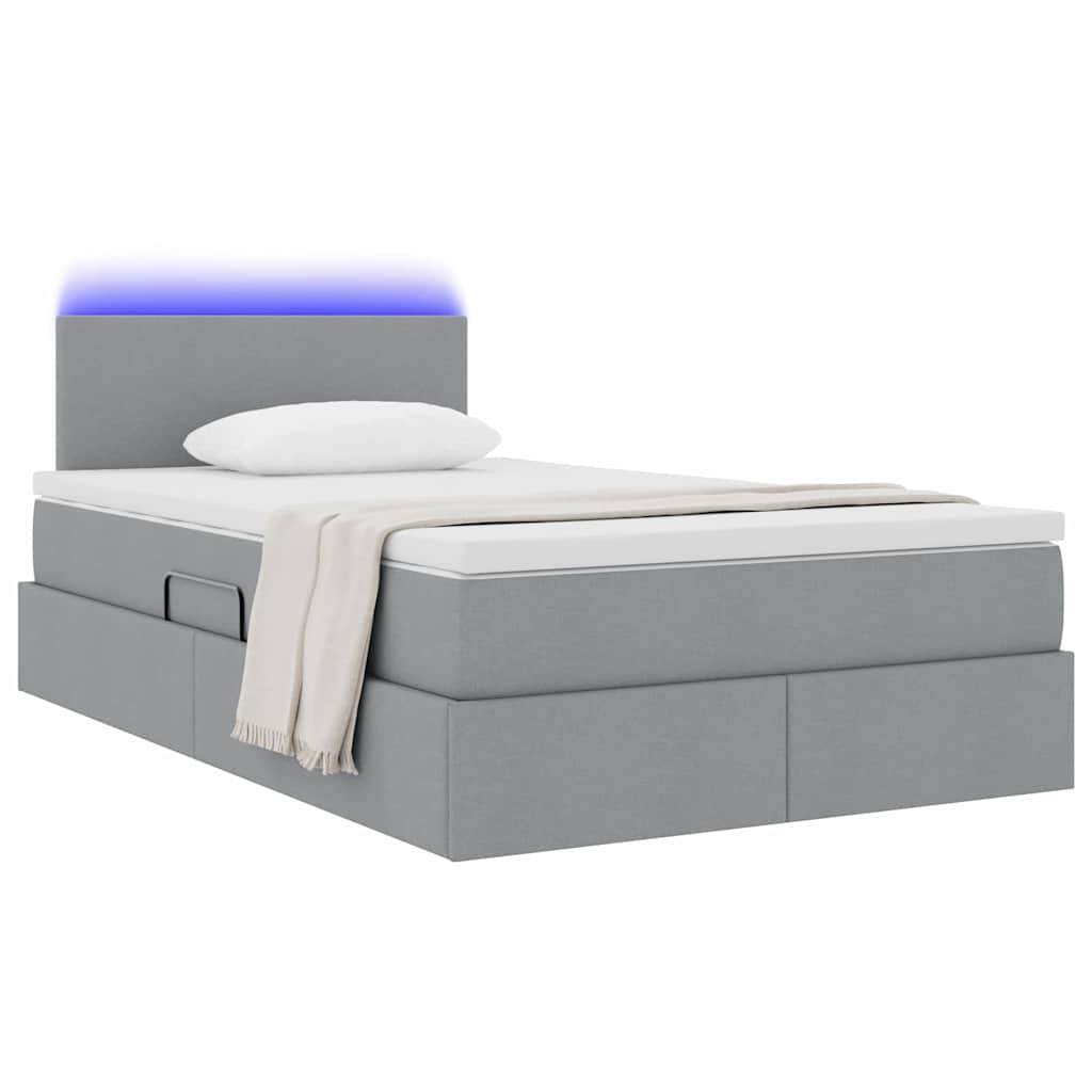 Ein modernes graues Plattformbett mit beleuchtetem Kopfteil, das weiches LED-Licht ausstrahlt, mit einem weißen Kissen und einer beigefarbenen Decke, die darüber drapiert ist.