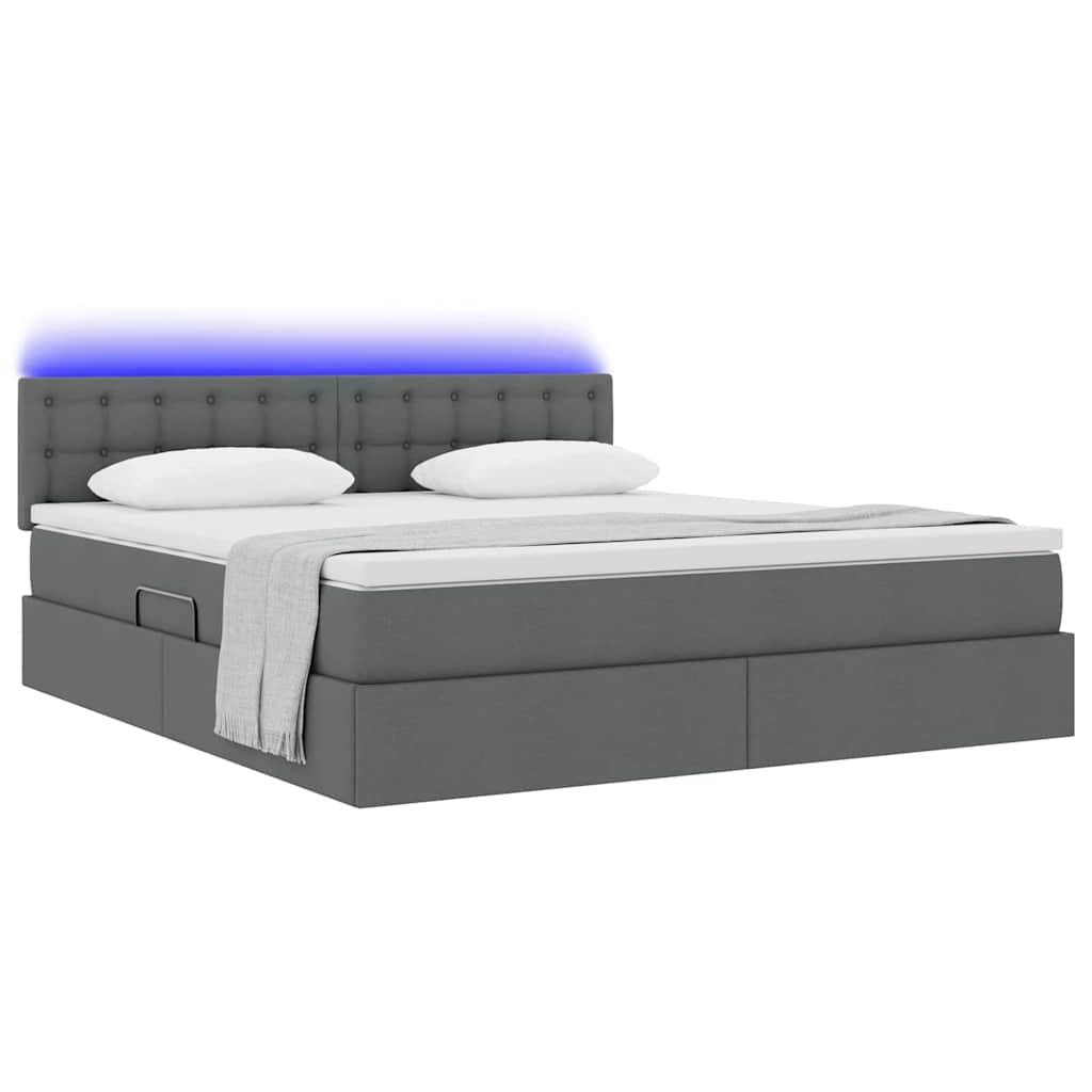 Ein modernes graues Plattformbett mit gepolstertem Kopfteil, das Stauraum unter dem Bett bietet und zwei weiße Kissen aufweist. Eine graue Decke ist ordentlich über der Kante drapiert.