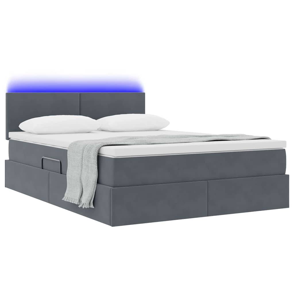Ein modernes graues Bett mit gepolstertem Kopfteil, blauer Hintergrundbeleuchtung, weißer Bettwäsche und einer gefalteten grauen Decke oben darauf.