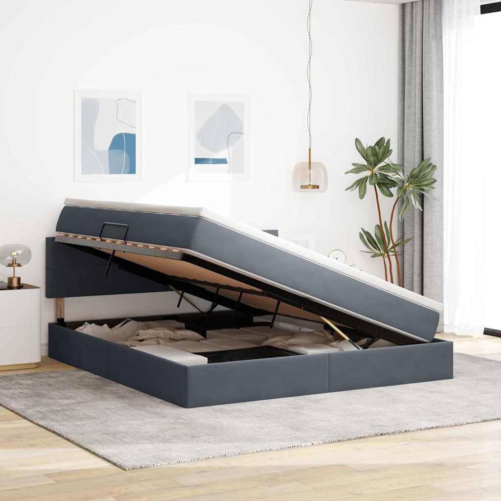 Ein Schlafzimmer mit einem grauen gepolsterten Bett, das einen Stauraum unter dem Bett mit geöffnetem Deckel aufweist. Enthält moderne Einrichtung und ein großes Fenster mit Vorhängen.
