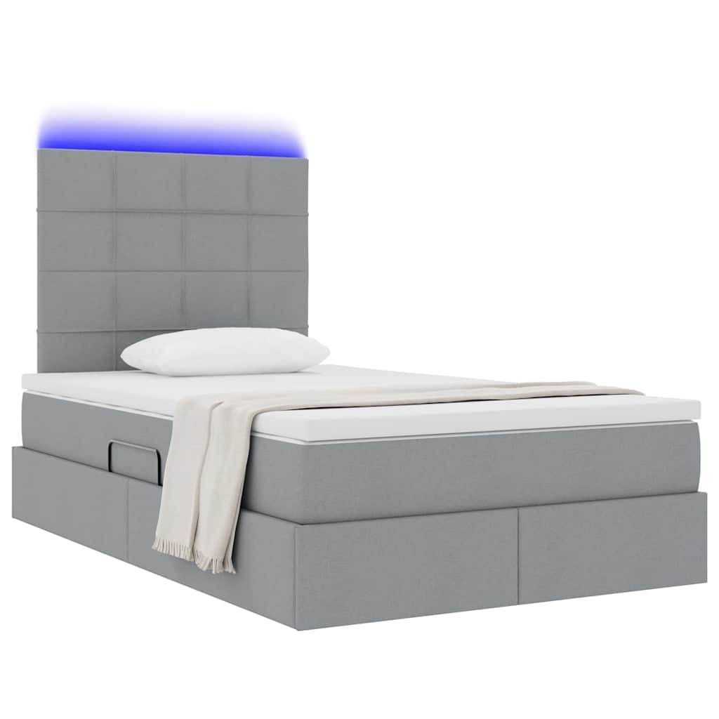 Ein modernes graugepolstertes Bett mit einem hohen, gepolsterten Kopfteil und blauer LED-Beleuchtung. Ein Kissen und eine beige Decke liegen auf der Matratze.