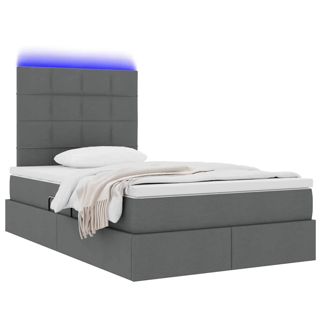 Ein modernes graues Bett mit einem hohen Kopfteil, das mit blauer LED-Beleuchtung ausgestattet ist. Das Bett hat eine Stoffpolsterung und ist ordentlich mit weißer Bettwäsche und einer hellgefärbten Wurfdecke gemacht.