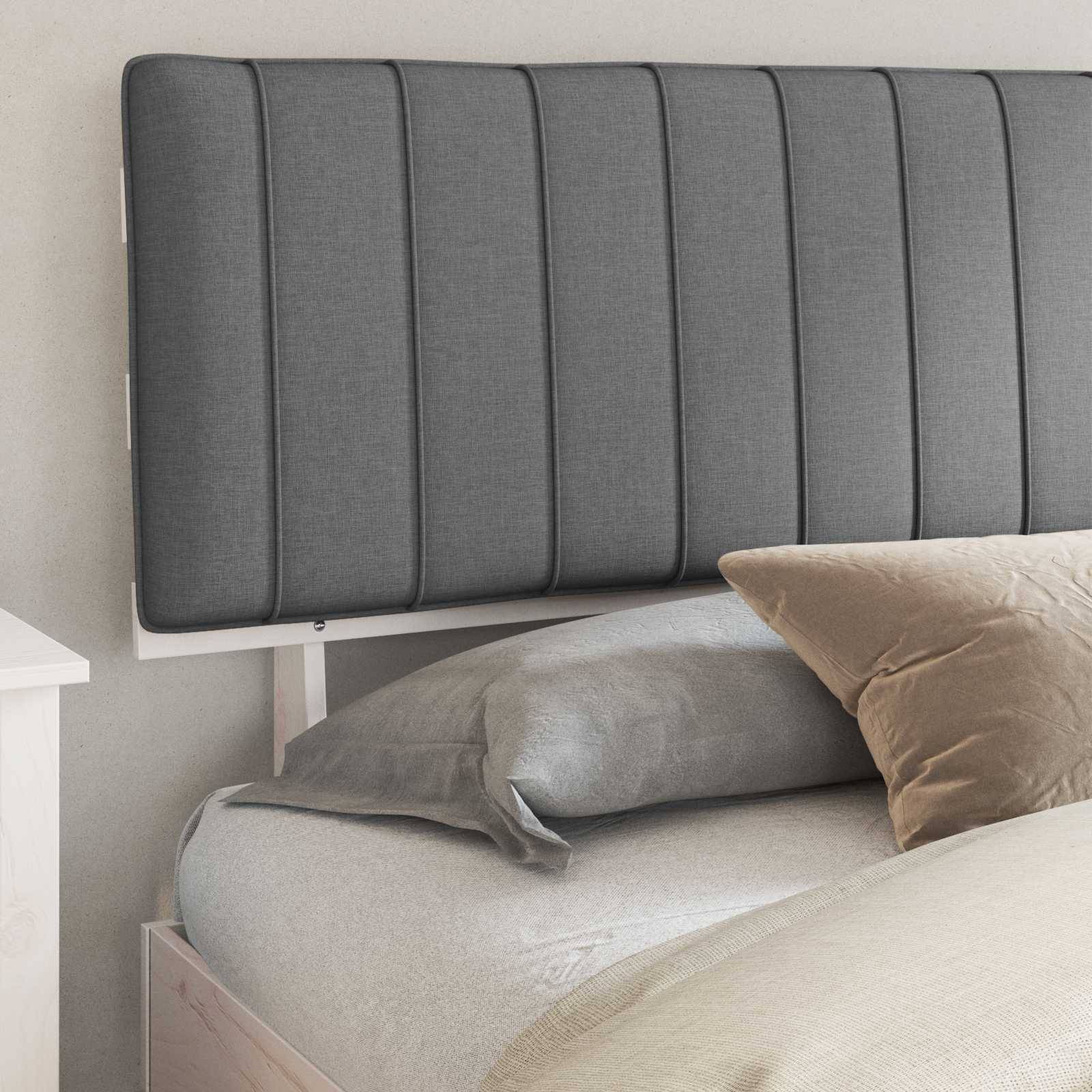 Ein sauber gemachtes Bett mit einem grauen gepolsterten Kopfteil, einem grauen Kissen und einem beigen Kissen, vor einer hellen Wand, was ein modernes Schlafzimmer andeutet.