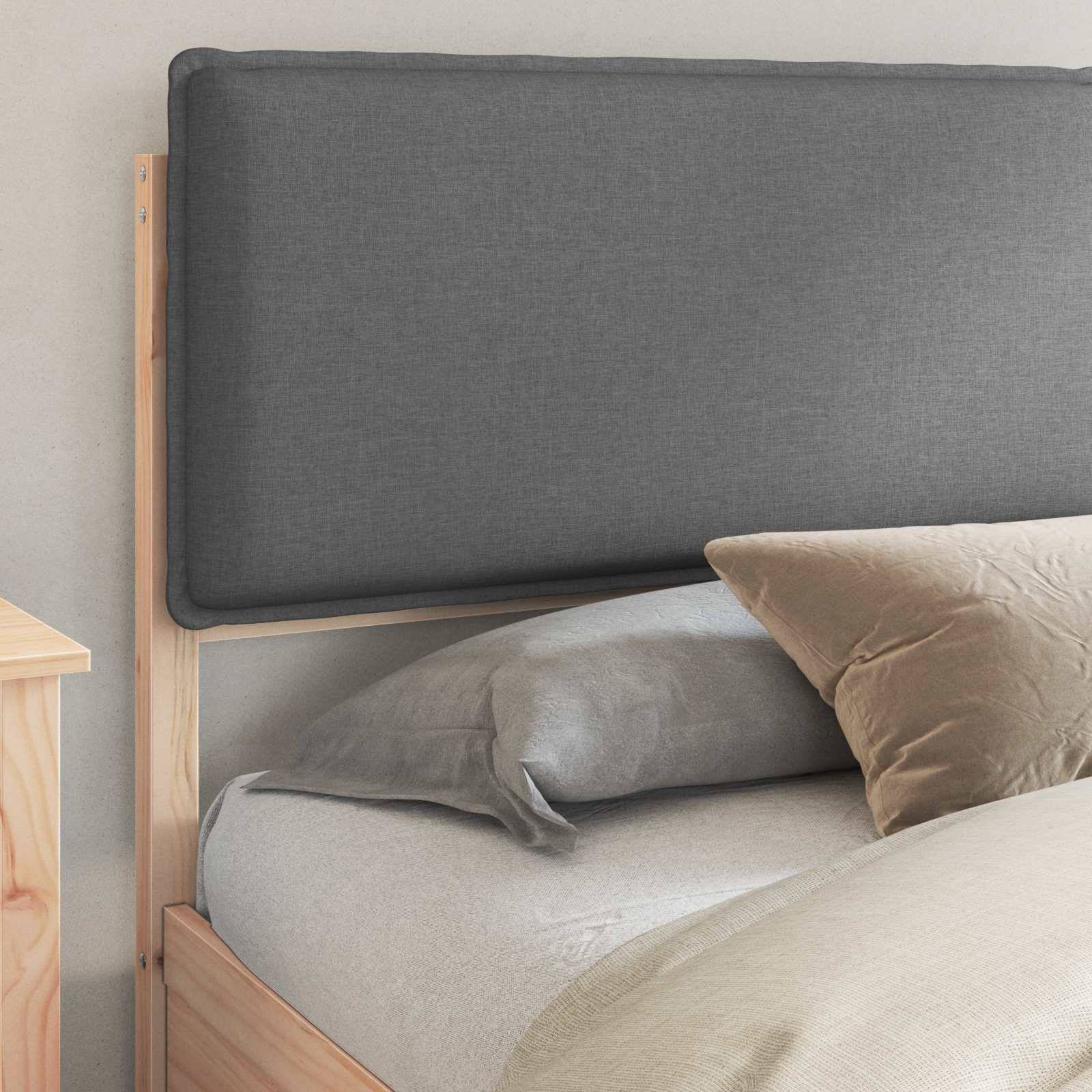 Ein ordentlich gemachtes Bett mit hellgrauer Bettwäsche, zwei beigen Kissen und einem gepolsterten Kopfteil. Ein kleiner Holznachttisch ist teilweise zu sehen.