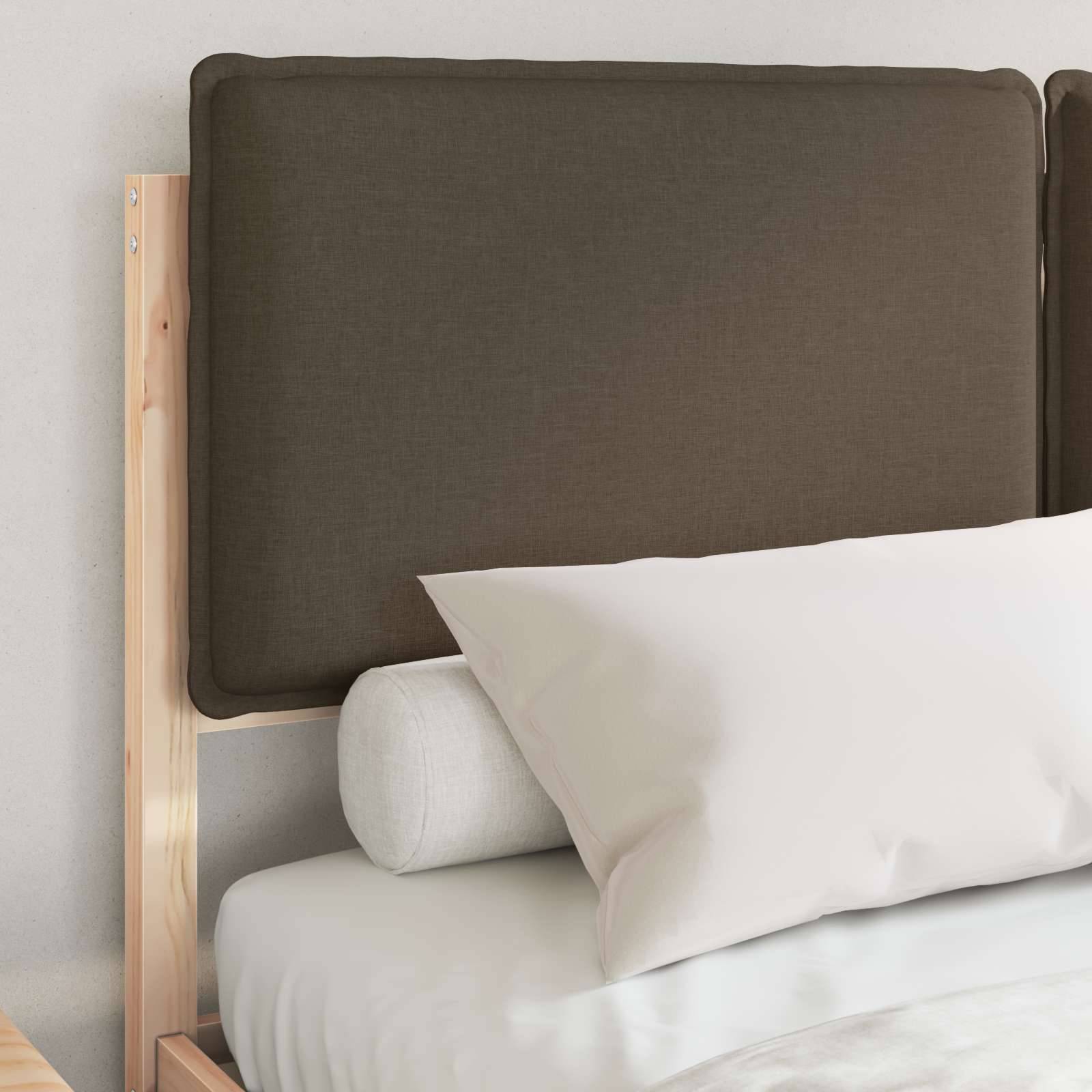 Ein ordentlich gemachtes Bett mit weißem Kissen und beigefarbenen Kissen vor einem braunen gepolsterten Kopfteil, eingesetzt in einen Holzrahmen. Schlichtes, modernes Design.