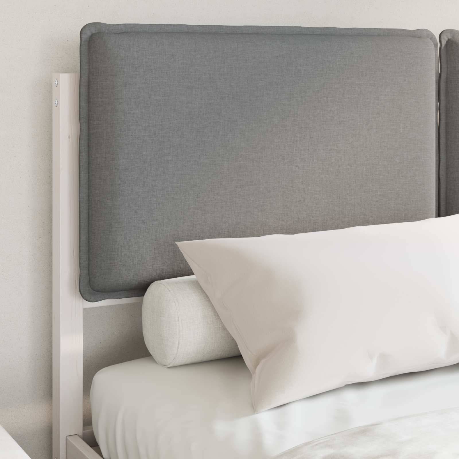 Ein ordentlich gemachtes Bett mit einem weißen Kissen, einem hellgrauen Kopfteil und weißer Bettwäsche in einem minimalistischen Raum.