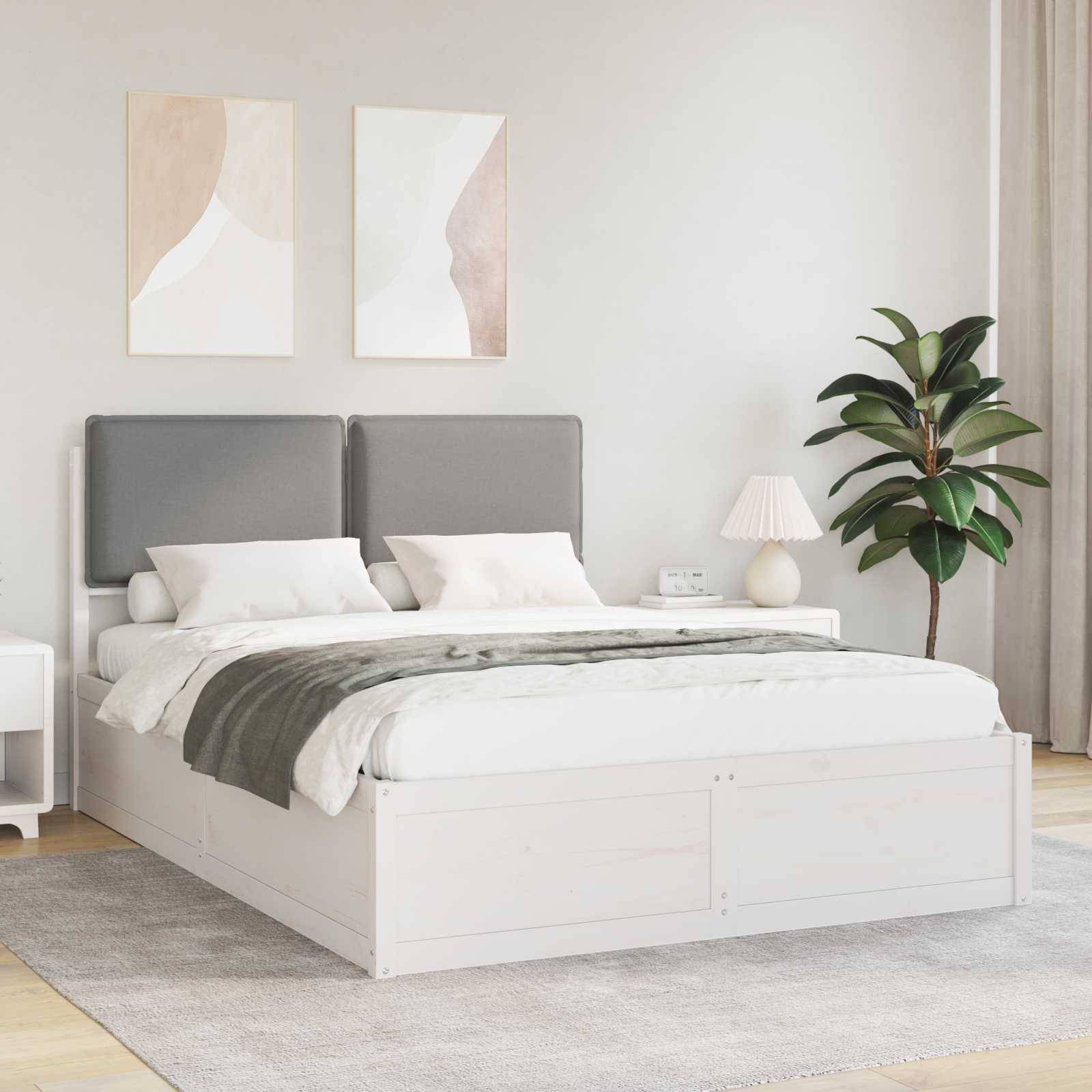 Ein modernes Schlafzimmer zeigt ein weißes Bett mit grauen Kissen, zwei abstrakte Wandkunstwerke darüber und eine Zimmerpflanze neben einem kleinen Nachttisch.