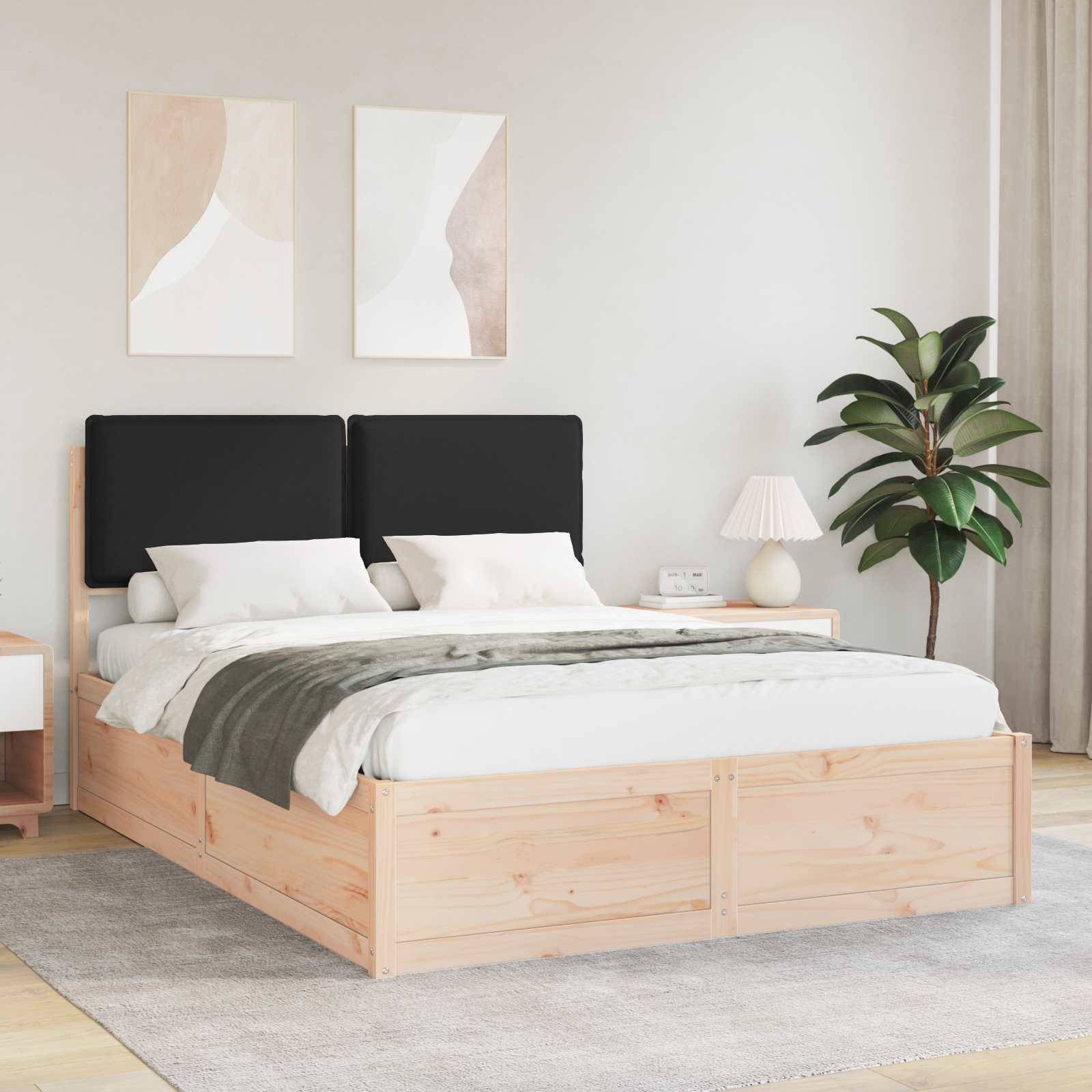 Ein modernes Schlafzimmer zeigt ein Holzbett mit schwarzen Kissen, weißer Bettwäsche, einem Nachttisch mit einer Lampe und einer großen Pflanze am Fenster.