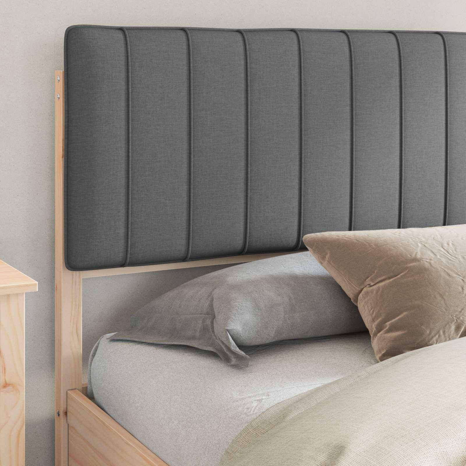 Ein modernes Schlafzimmer mit einem Holzbettgestell, einem grauen gepolsterten Kopfteil und einem beigen Kissen auf einem sorgfältig gemachten Bett.
