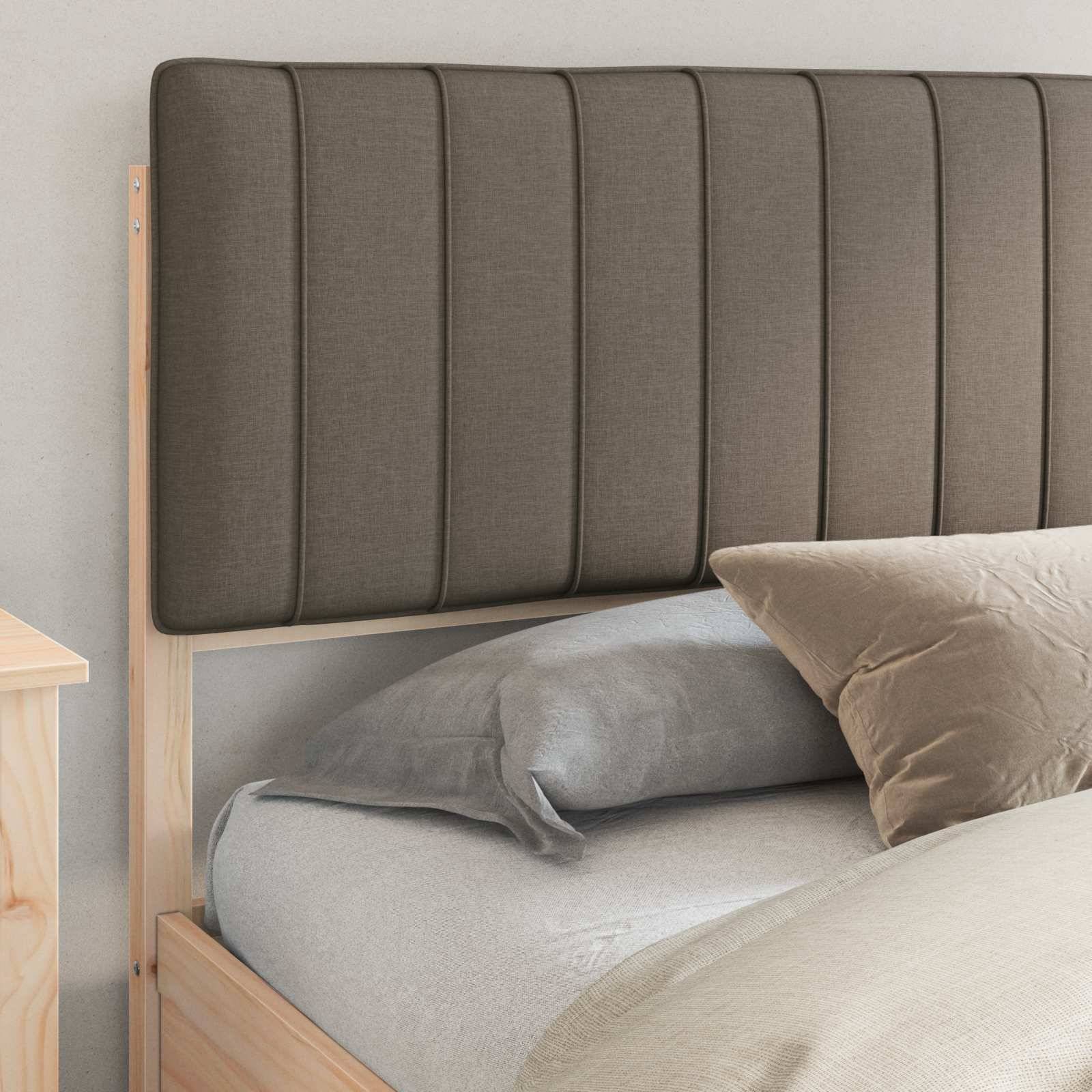 Ein ordentlich gemachtes Bett mit einem grauen Kissen und einer gesteppten Bettdecke, neben einem Holznachttisch. Der Kopfteil weist vertikale Steppnähte auf.