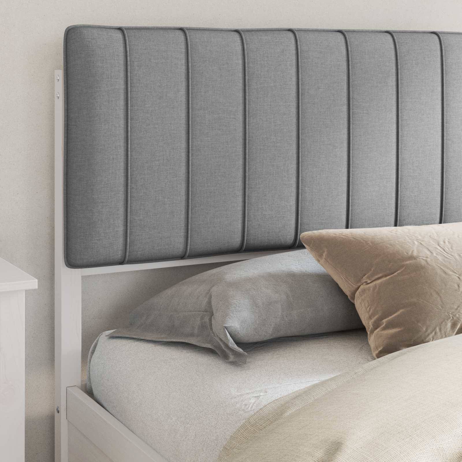 Ein ordentlich gemachtes Bett mit einer hohen, gepolsterten grauen Kopfseite, versehen mit einem grauen Kissen und einem beigen Kissen, in einem hell eingerichteten Schlafzimmer.