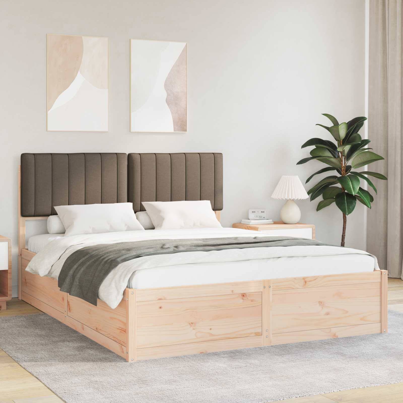 Ein modernes Schlafzimmer mit einem Holzbett, grau gepolstertem Kopfteil und weißer Bettwäsche. Neben dem Bett steht ein Nachttisch mit einer Lampe und einer Pflanze.