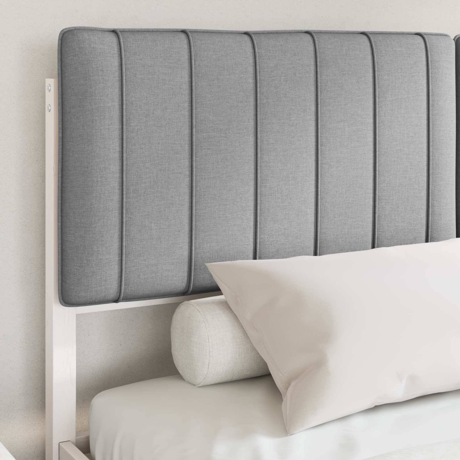 Ein Bett mit einem grauen Paneelkopfteil, einem hellgrünen zylindrischen Nackenrollo und einem rechteckigen beigen Kissen.