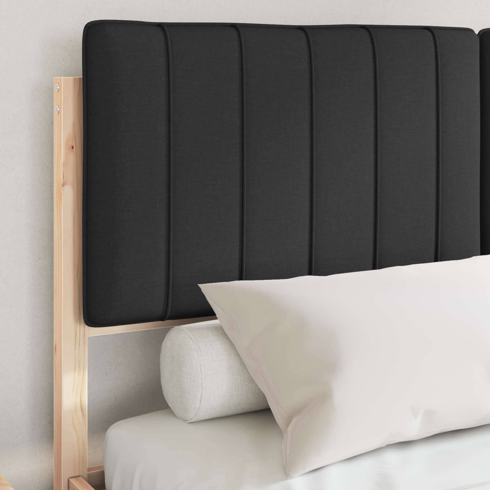 Ein sorgfältig bezogenes Bett mit weißen Kissen und einem hellgrauen Laken, das vor einem Holzkopfteil mit einer dunklen gepolsterten Tafel steht.