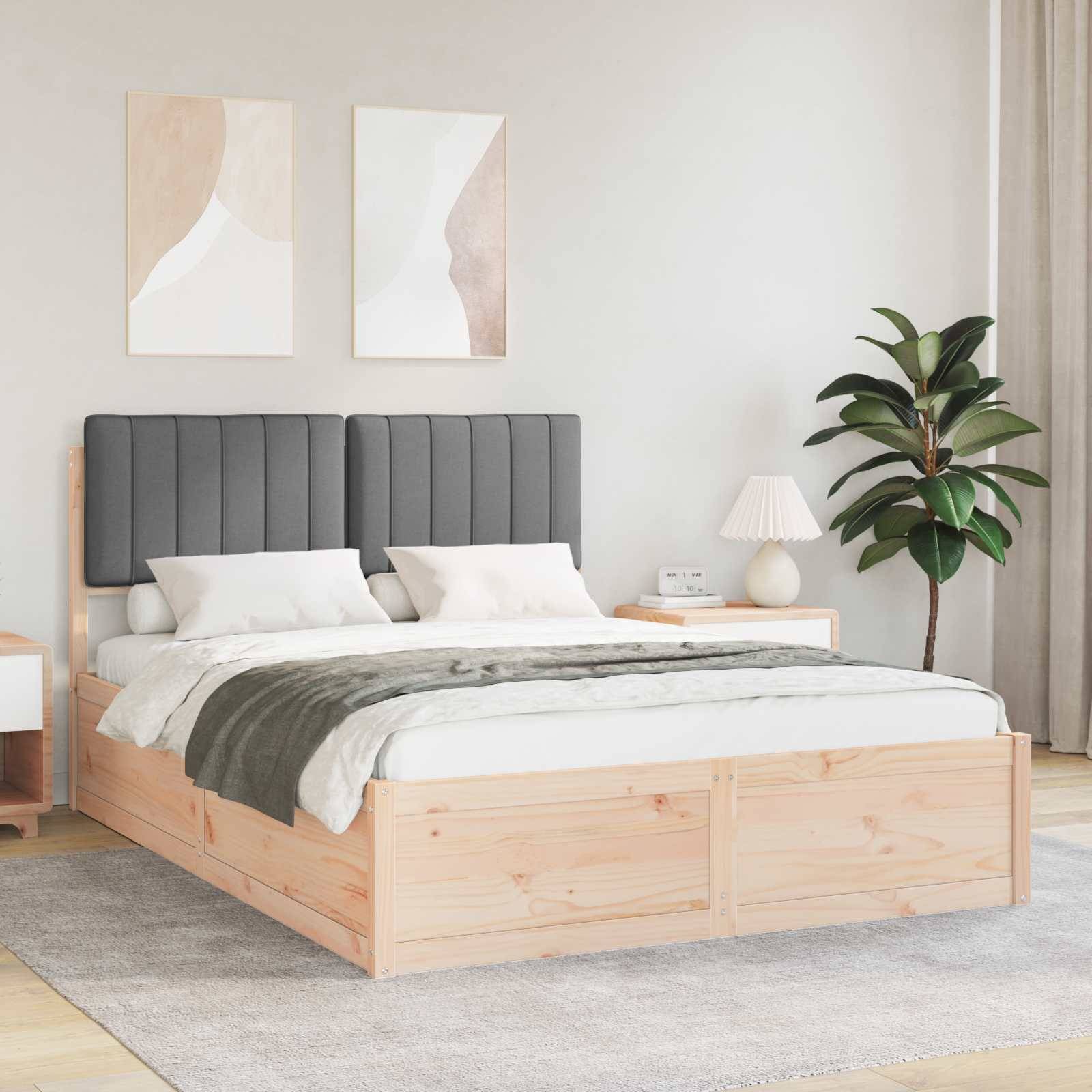Ein modernes Schlafzimmer mit einem Holzbett, einem grauen gepolsterten Kopfteil, weißer und grauer Bettwäsche, zwei abstrakten Gemälden und einem Nachttisch mit einer Lampe.