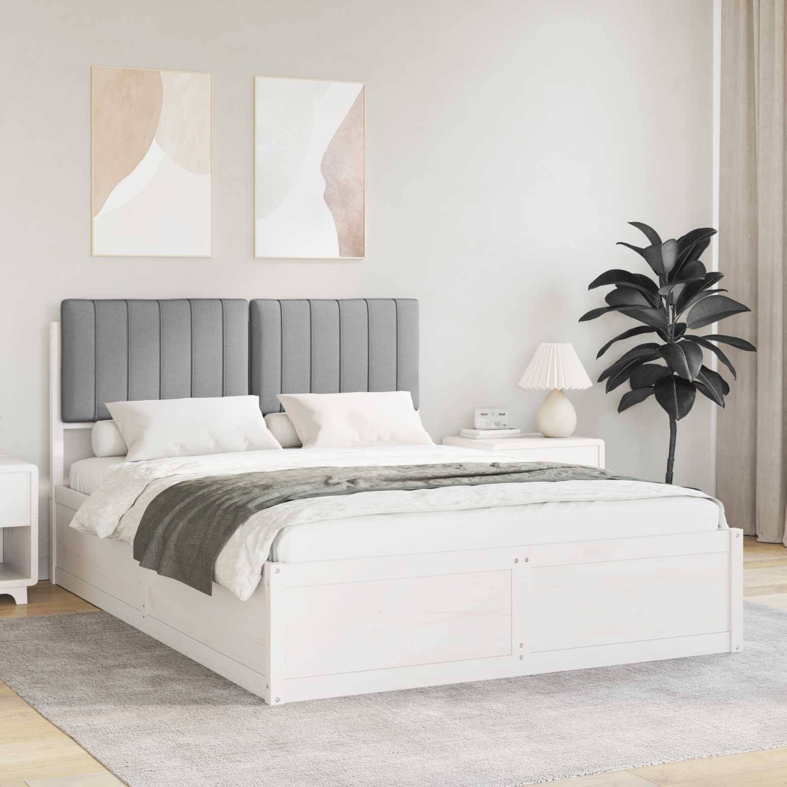 Ein modernes Schlafzimmer mit einem grau bezogenen Bett, weißer Bettwäsche und einer Pflanze an der Seite. Zwei abstrakte Kunstwerke hängen über dem Kopfteil.