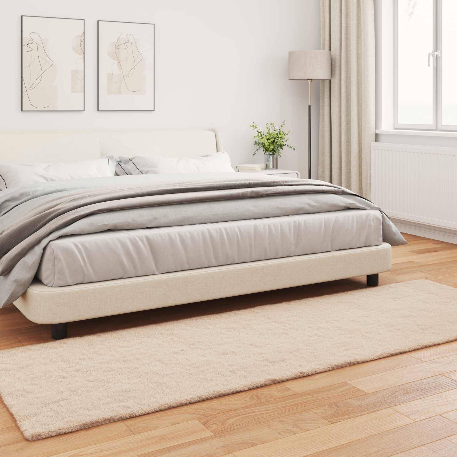 Ein minimalistisches Schlafzimmer mit einem großen, sauber gemachten Bett mit grauer und weißer Bettwäsche. Zwei abstrakte Kunstwerke hängen über dem Bett.
