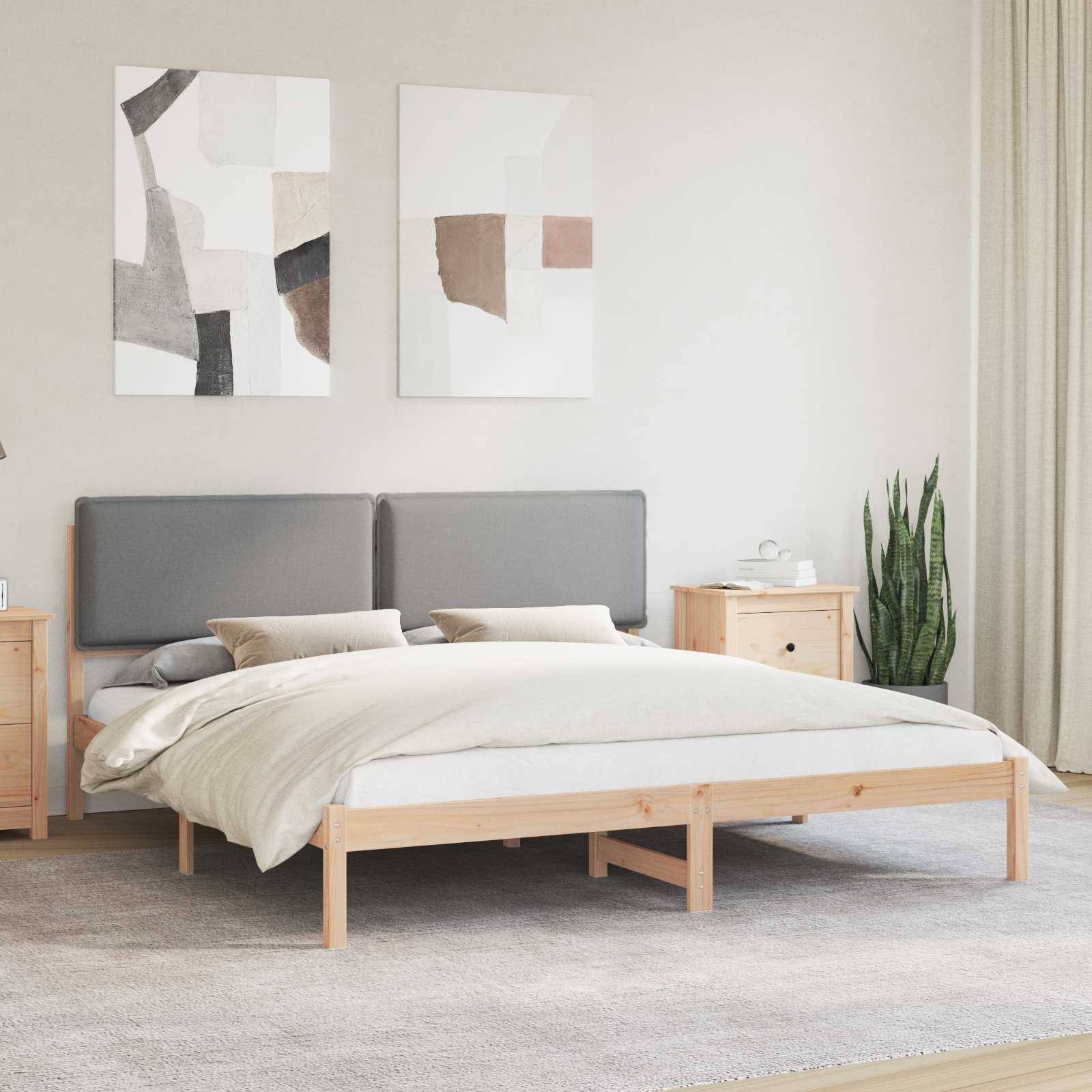 Ein minimalistisches Schlafzimmer mit einem Holzbett, grauem Kopfteil und neutraler Bettwäsche. Zwei abstrakte Gemälde hängen darüber. Eine Pflanze steht in der Ecke.