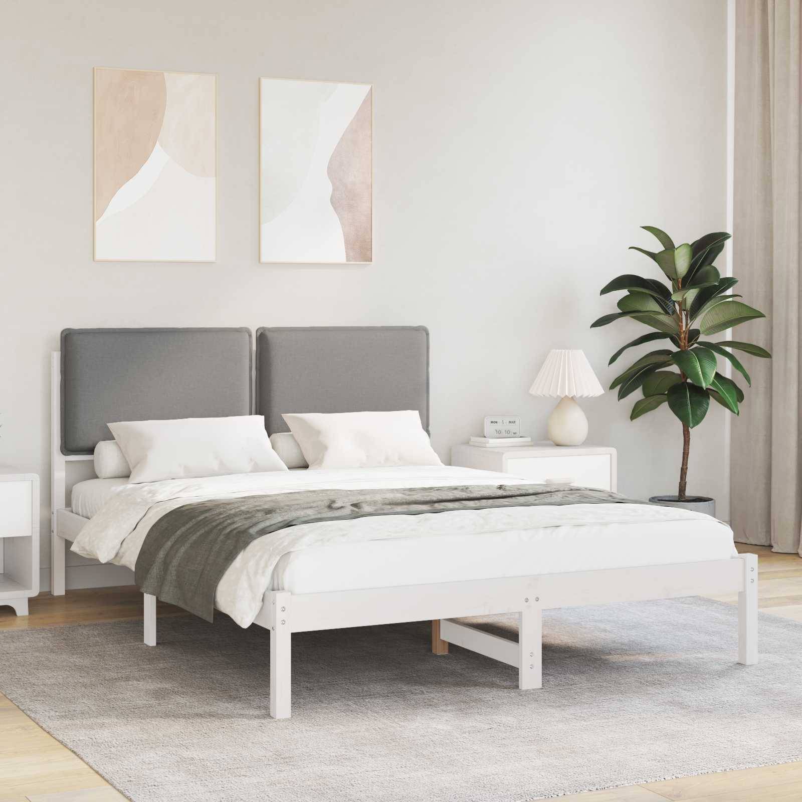 Ein modernes Schlafzimmer verfügt über ein Doppelbett mit grauem Kopfteil, weißer Bettwäsche und einer grünen Tagesdecke. Zwei abstrakte Kunstwerke hängen über dem Bett.