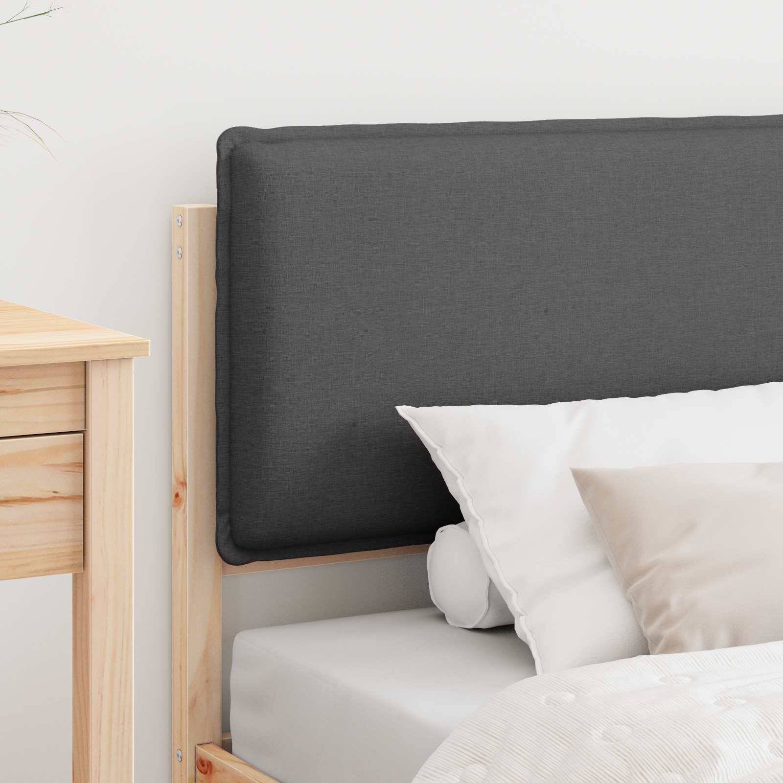 Ein minimalistisches Schlafzimmer mit einem Holzbettgestell, grauem gepolstertem Kopfteil und weißer Bettwäsche, einschließlich grauer und beiger Kissen. Ein hölzerner Nachttisch ist teilweise sichtbar.