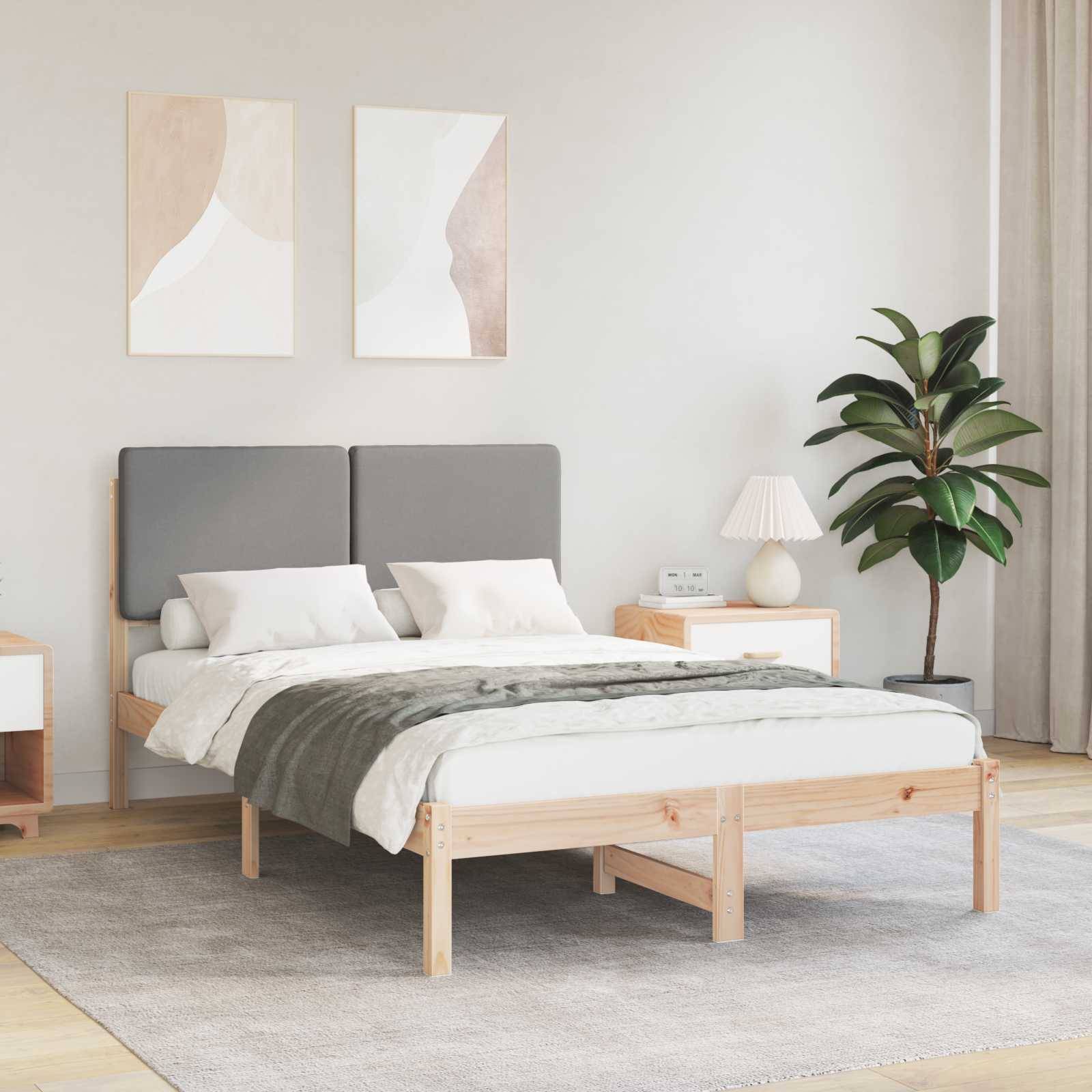Ein minimalistisches Schlafzimmer mit einem Doppelbett, einem grauen Kopfteil und weißer Bettwäsche. Zwei abstrakte Gemälde hängen an der Wand. Eine Topfpflanze steht in der Ecke.