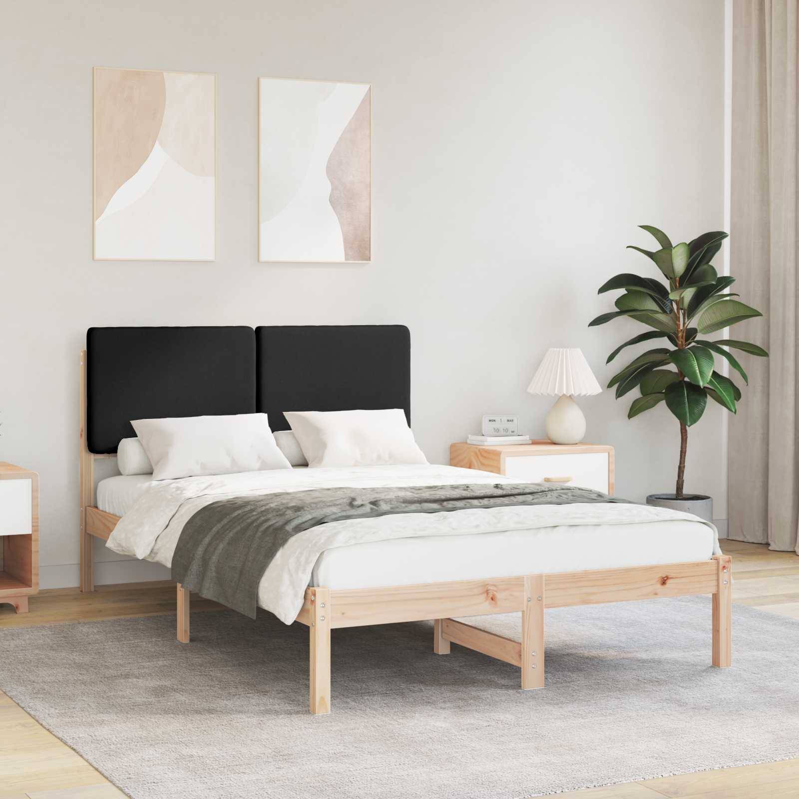 Ein modernes Schlafzimmer mit einem Holzbett, schwarzen Kopfteilen, weißer Bettwäsche, einem Nachttisch mit einer Lampe, zwei abstrakten Gemälden und einer Zimmerpflanze.